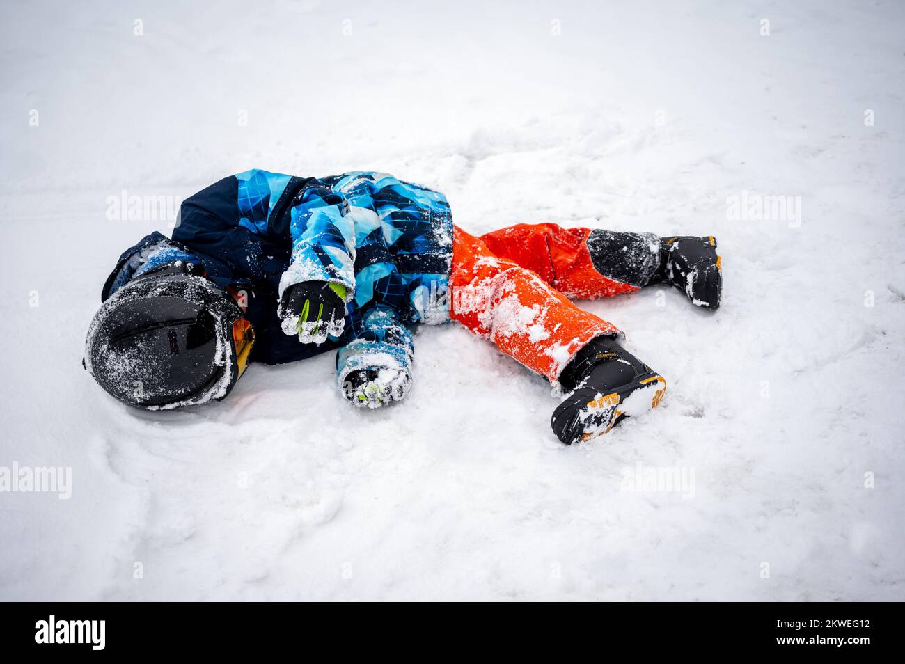 Persona con snowboard sulla neve. Un bambino asiatico sta cadendo sul terreno. Sport invernali con spazio copia. Foto Stock