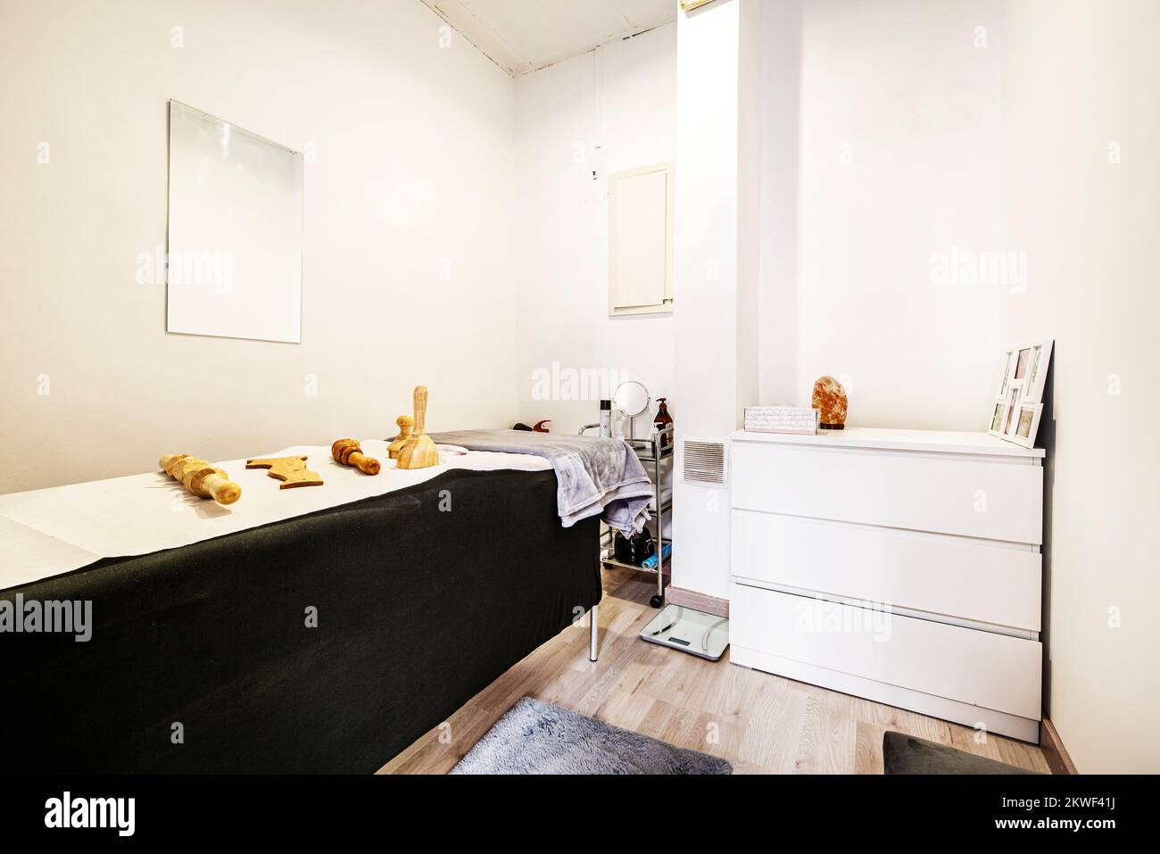 Cabina di un salone di bellezza con un tavolo coperto da un panno nero elasticizzato e una cassettiera bianca Foto Stock