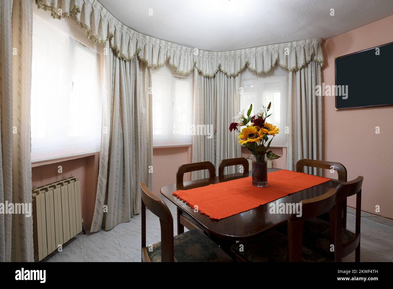 Soggiorno di una casa con angolo dedicato ad una sala da pranzo con tavolo in legno e sei sedie abbinate in una sala semicircolare Foto Stock