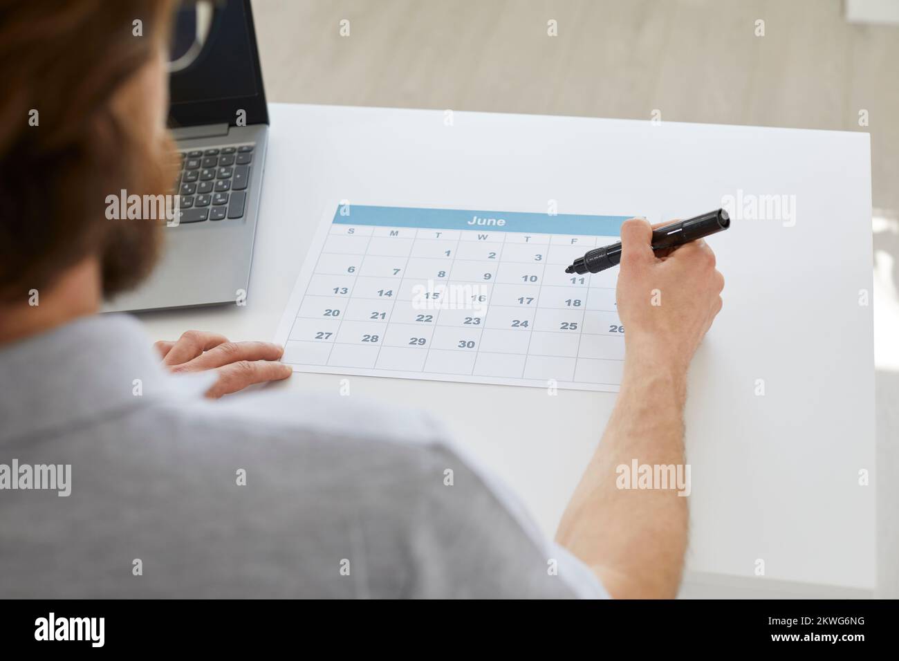 Uomo d'affari seduto alla sua scrivania e utilizzando un calendario per organizzare il suo programma d'affari Foto Stock