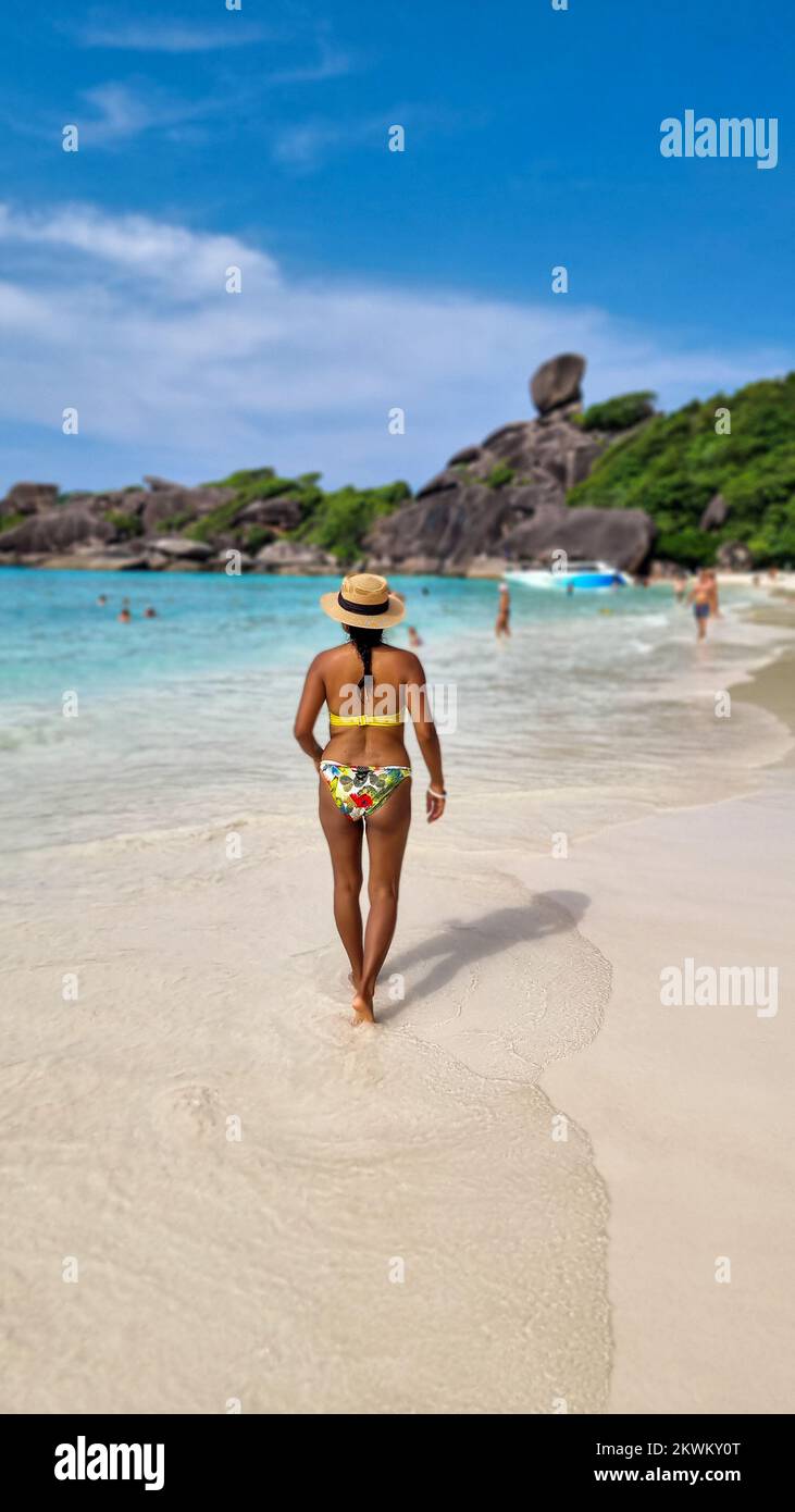 Donne asiatiche che si adagiano sulla spiaggia bianca tropicale con l'oceano color turqouse delle Isole Similan Thailandia. Foto Stock