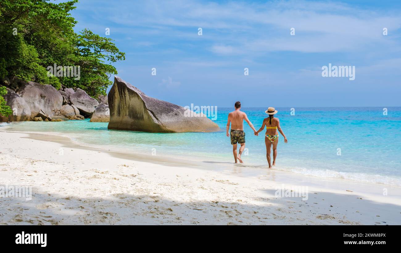 Un paio di uomini e donne che camminano sulla spiaggia bianca tropicale con l'oceano color serra delle isole Similan Thailandia. Foto Stock