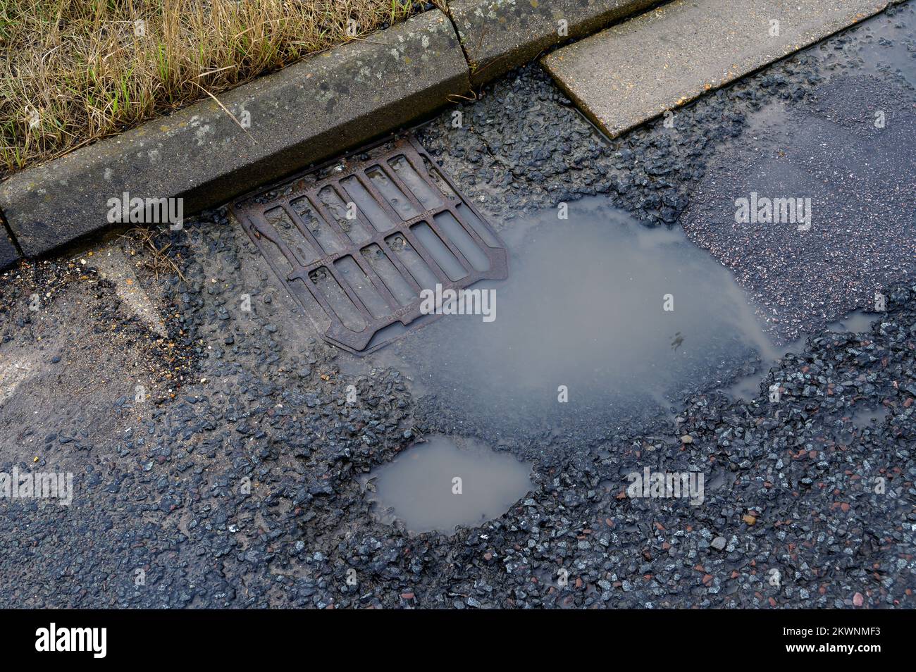 Scolo e pohole bloccati in una strada mal mantenuta in Inghilterra. Foto Stock