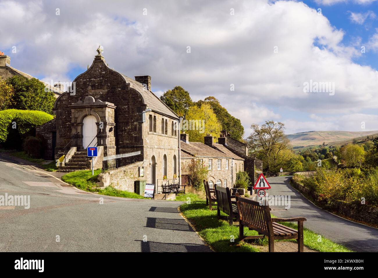 Panchine del Muker Literary Institute e cottage in pietra calcarea nel villaggio nello Yorkshire Dales National Park. Muker, Swaledale, North Yorkshire, Inghilterra, Regno Unito Foto Stock