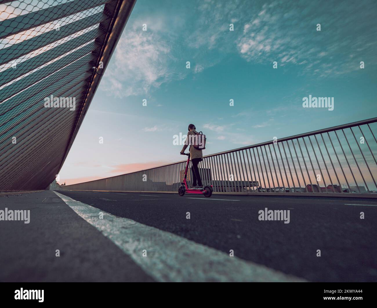 uomo sullo scooter elettrico, persona che cavalca attraverso il ponte Foto Stock