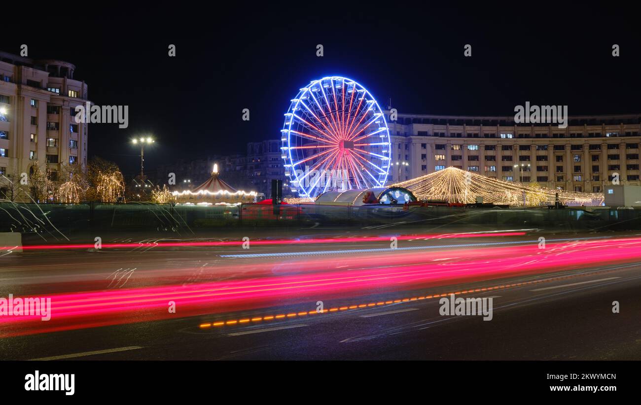 Natale vacanze ruota ferris a Bucarest, Romania, di notte, con auto luci sentieri. Foto Stock
