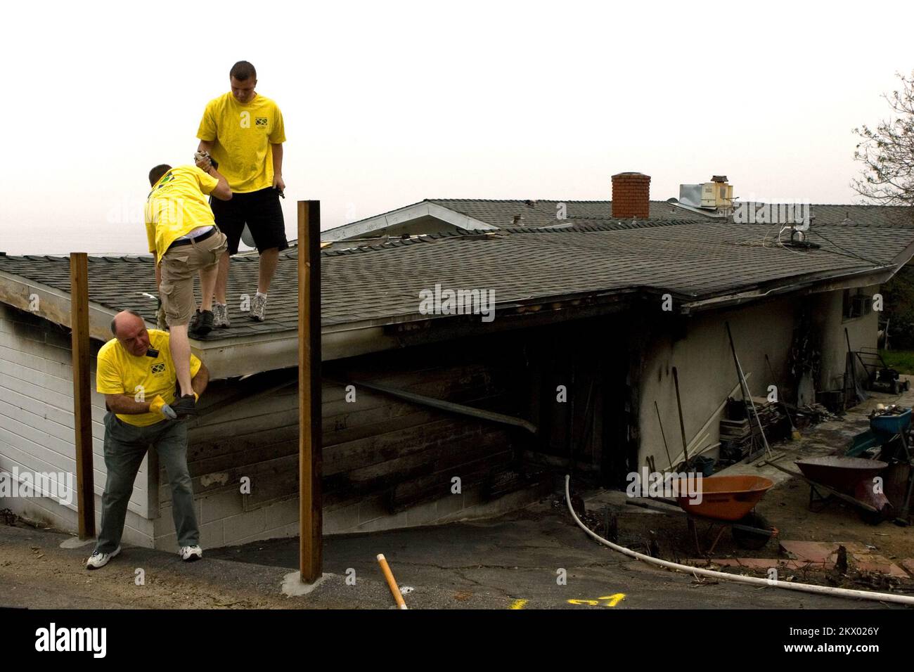 Wild Fires, Malibu, CA, 16th novembre 2007 Presidente Blackburn, E gli anziani Smith e Tuggle della Chiesa Mormonica di Los Angeles si arrampicano su questa casa per aiutare a ripulire e rimuovere i detriti dalla casa dei membri della Chiesa Don Konold e della moglie Annemarie. Le loro case erano una delle poche case danneggiate dal fuoco del canyon di Malibu. Fotografie relative a disastri e programmi, attività e funzionari di gestione delle emergenze Foto Stock