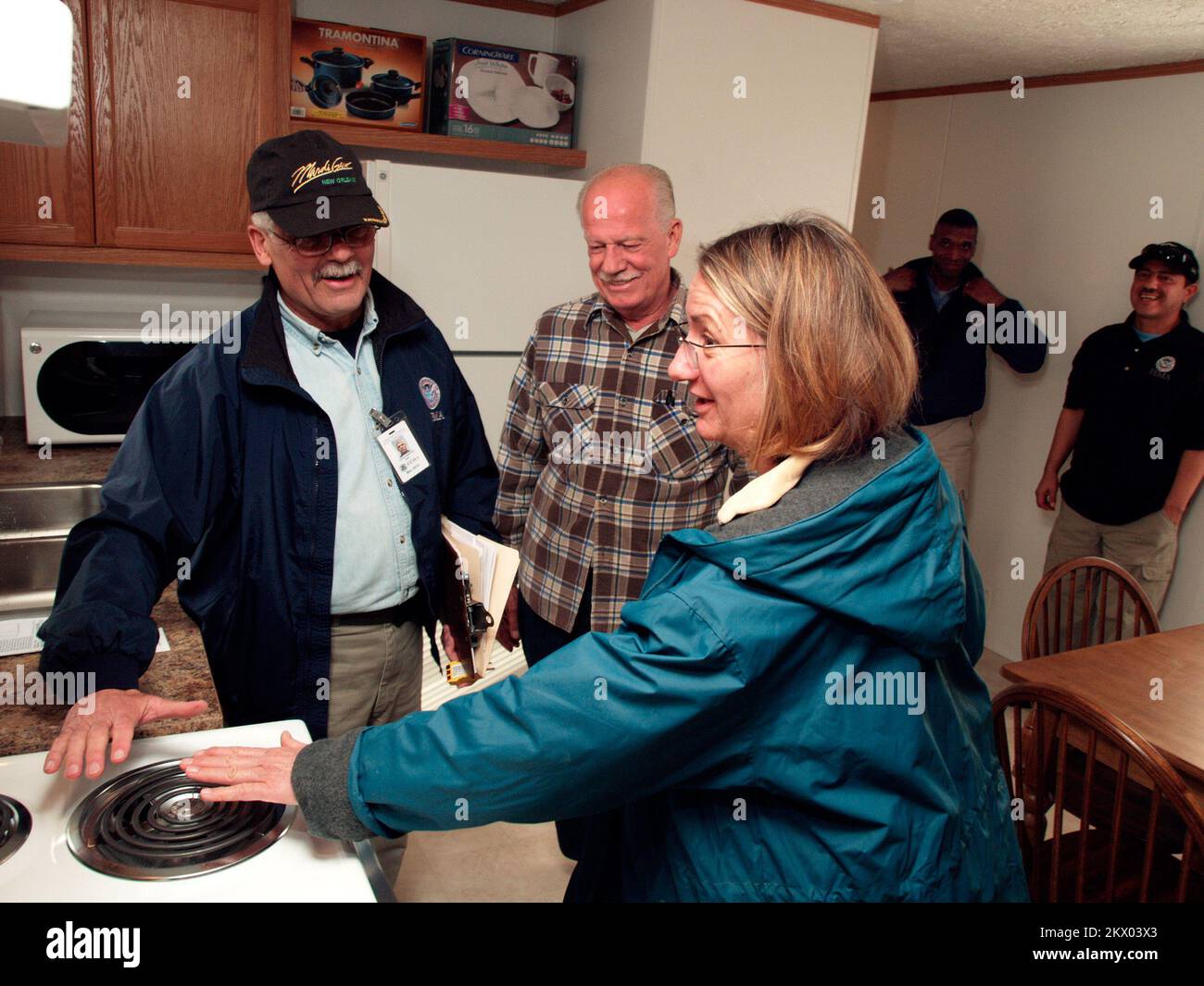 Incendi selvatici, Delzura, CA, 8 dicembre 2007 FEMA┬Æ Louis Narciso, operazioni abitative dirette (assistenza individuale) di sinistra, e Leighann Grice, prova la stufa all'interno della casa mobile FEMA ha fornito lei e suo marito Jon, centro, temporaneamente chiamare a casa. Dietro di loro osservano i lavoratori della FEMA Kenneth Tingman, a sinistra, assistente speciale delle operazioni, e Henry Colon, un monitor tecnico. La coppia ha perso la loro casa e molti possedimenti domestici quando i fuochi selvatici hanno bruciato la loro comunità in ottobre. Amanda Bicknell/FEMA.. Fotografie relative alle catastrofi e ai programmi e alle attività di gestione delle emergenze; Foto Stock