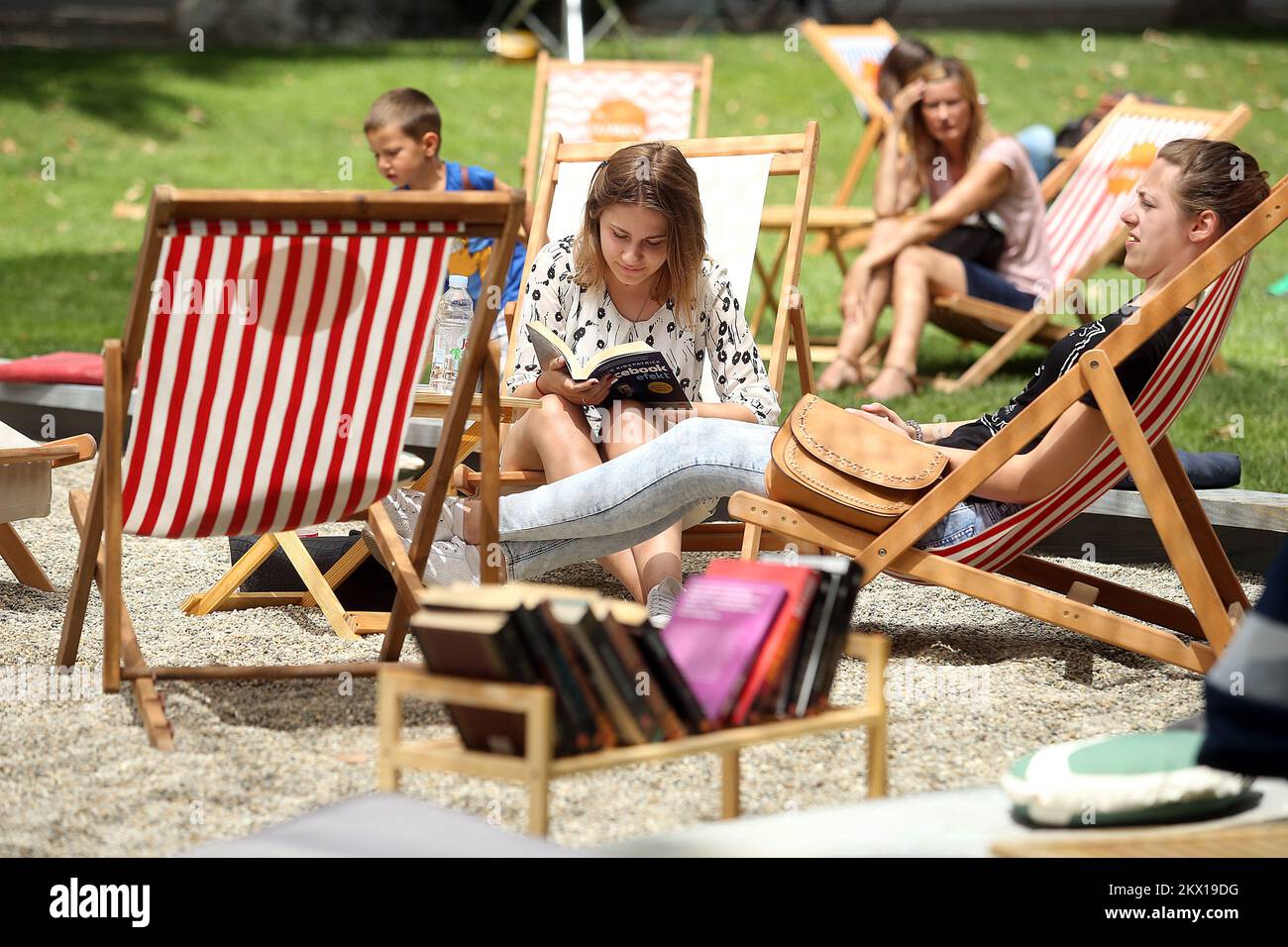 03.07.2017., Zagabria, Croazia - per il terzo anno consecutivo, la casa editrice Lumen organizza una fiera del libro che trasforma il Parco Zrinjevac di Zagabria in un'oasi per i bookworm e i futuri booklovers. Il parco è coperto di sabbia, ci sono ombrelloni e sedie a sdraio in modo che i visitatori possono leggere più di 200 libri gratuiti all'ombra, così come acquistare alcuni di loro a un prezzo scontato. I visitatori possono rinfrescarsi con uno dei cocktail ispirati ai titoli di libri che si possono trovare sulla spiaggia di Lumen. Foto: Goran Stanzl/PIXSELL Foto Stock