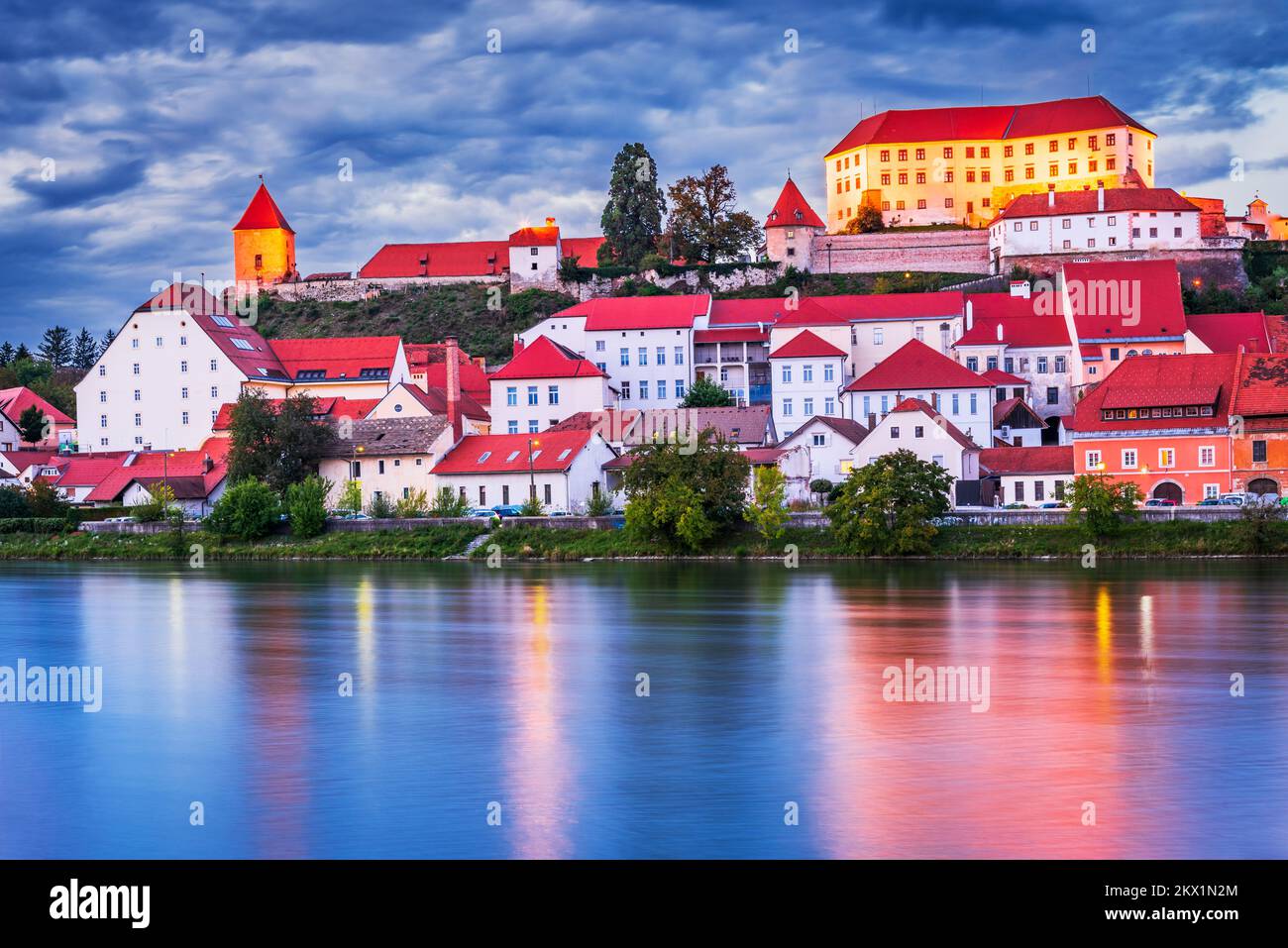 Ptuj, Slovenia. Scena notturna con la bellissima città più antica della Slovenia, la storica Stiria, il fiume Drava riflessione d'acqua con il castello in cima alla collina. Foto Stock