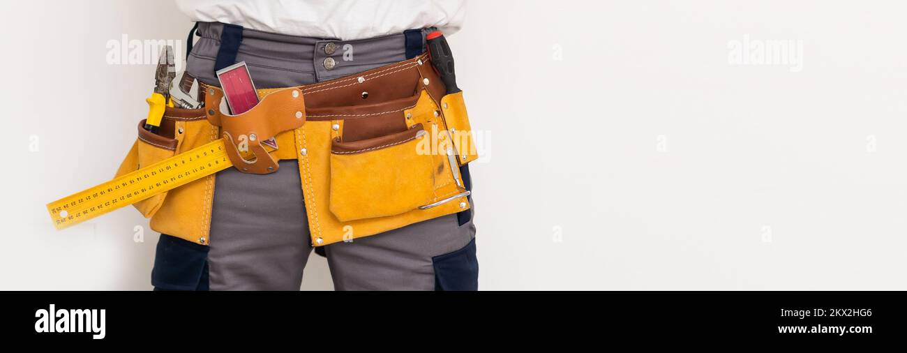 Maschio con cintura piena di strumenti manuali per la riparazione di casa. Isolato su sfondo grigio Foto Stock