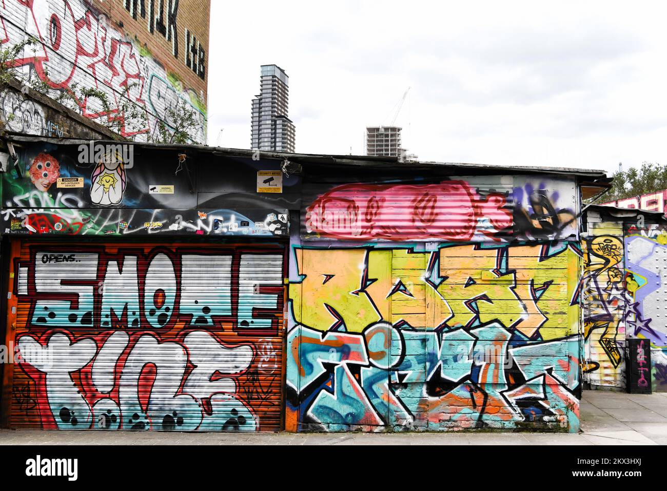 Graffiti su Brick Lane con appartamenti dietro Shoreditch London Foto Stock