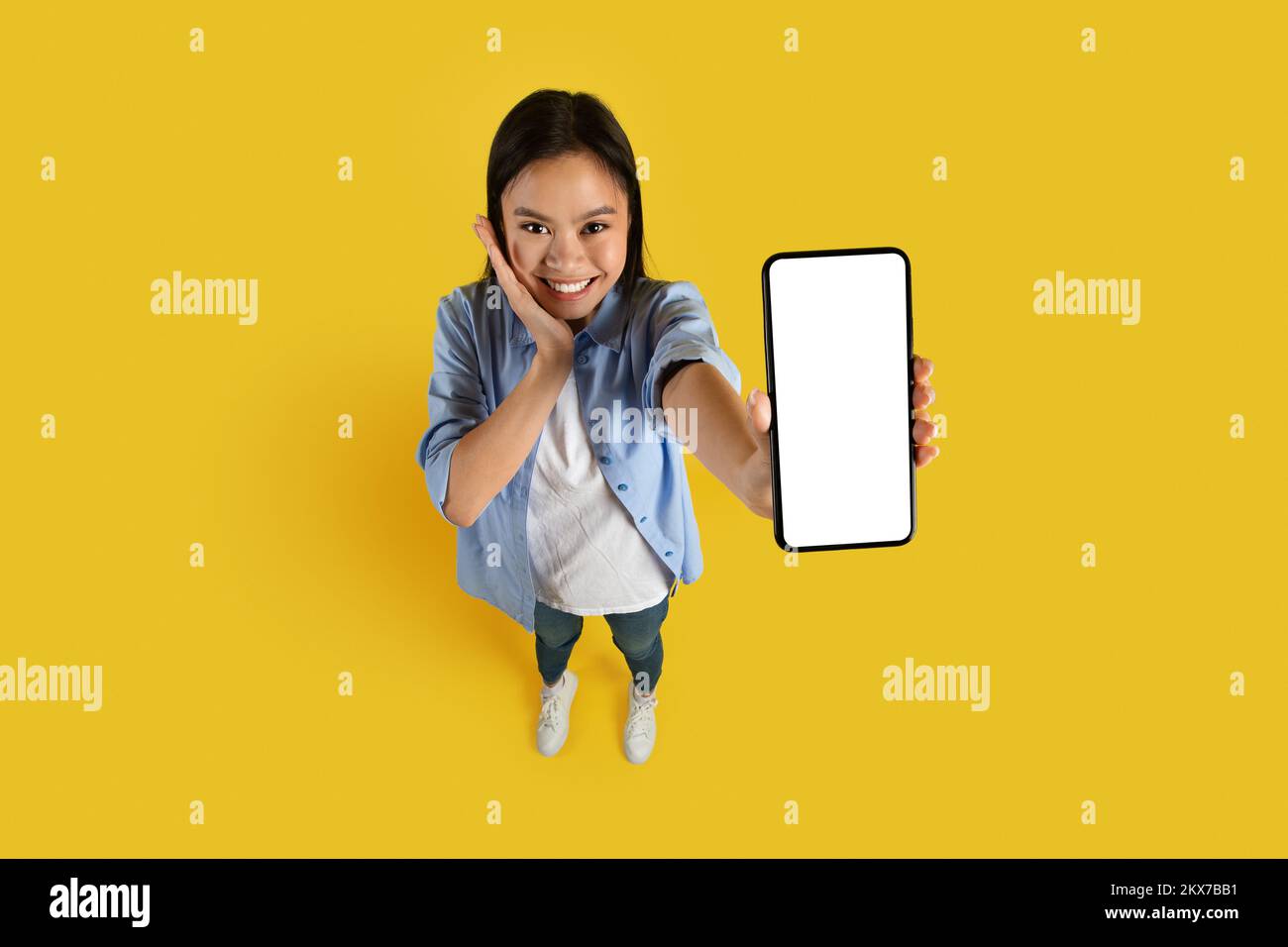 Emozione umana, non può credere. Felice sorpreso cute studente donna coreano millenario in casual show smartphone Foto Stock