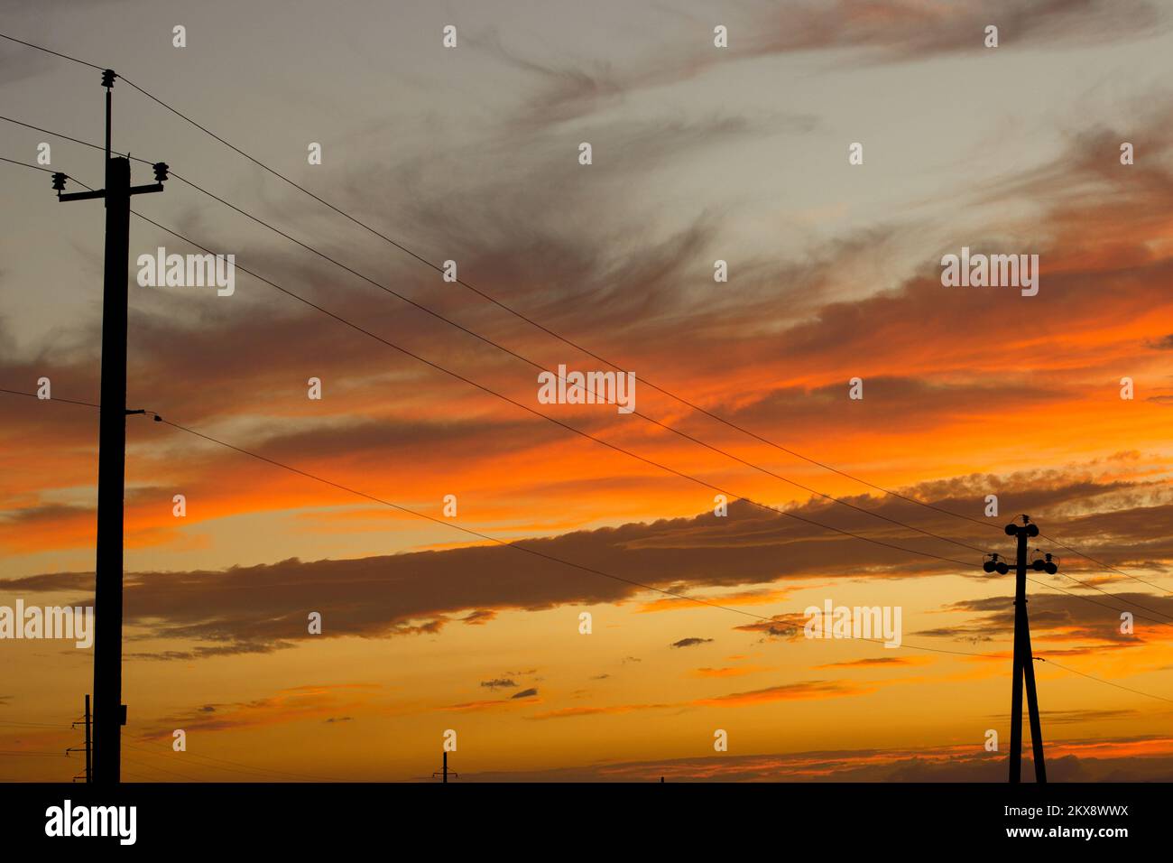 Linee elettriche contro un bel cielo arancione brillante in serata Foto Stock