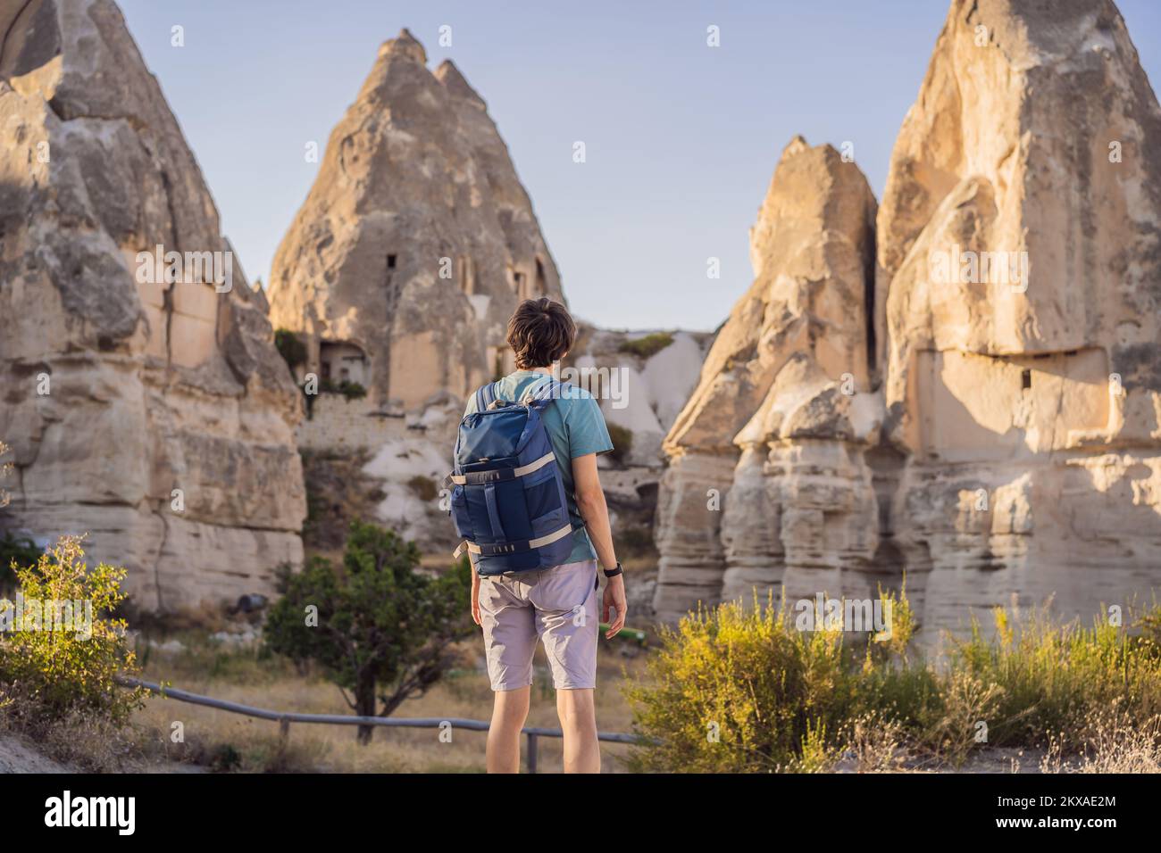 Uomo turistico sullo sfondo di formazioni geologiche uniche in Love Valley in Cappadocia, popolare destinazione di viaggio in Turchia Foto Stock
