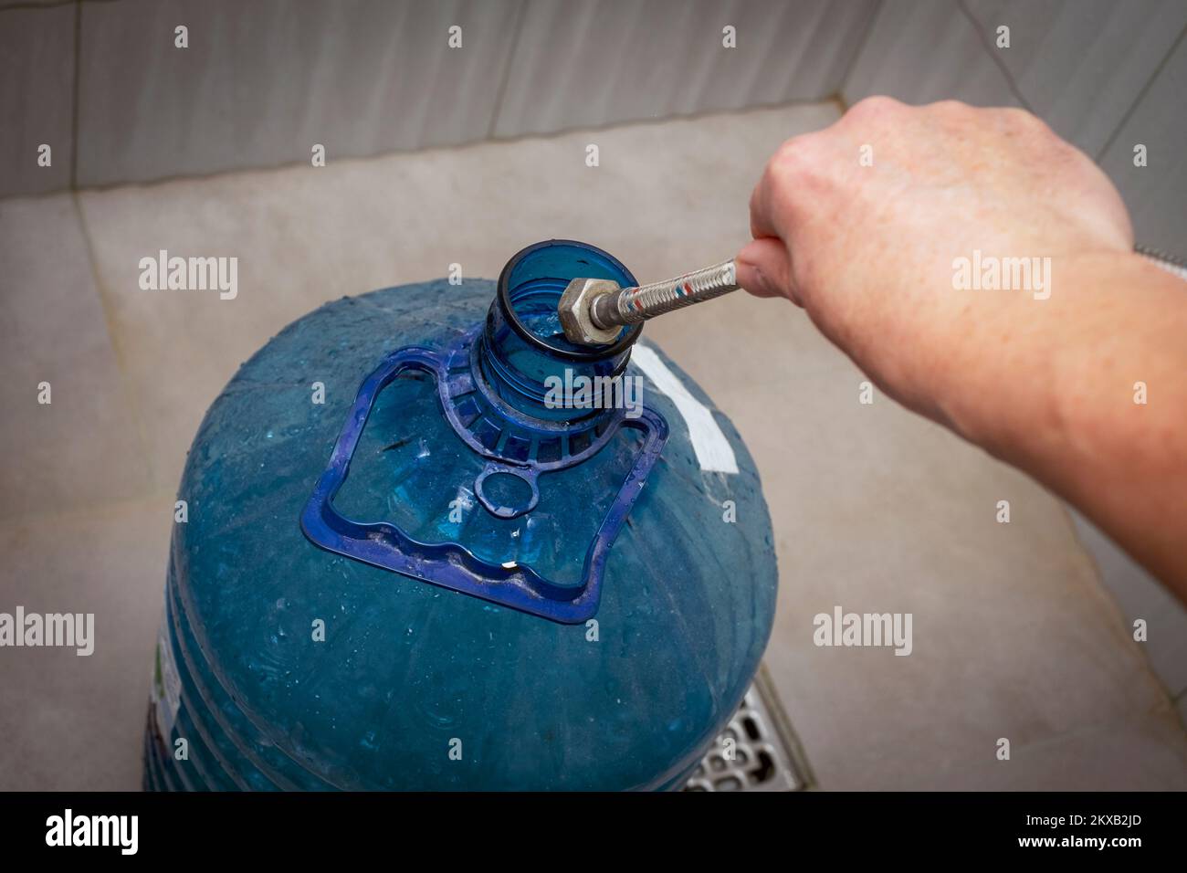 primo piano di una mano maschio che riempie una bottiglia di plastica con acqua da riservare Foto Stock