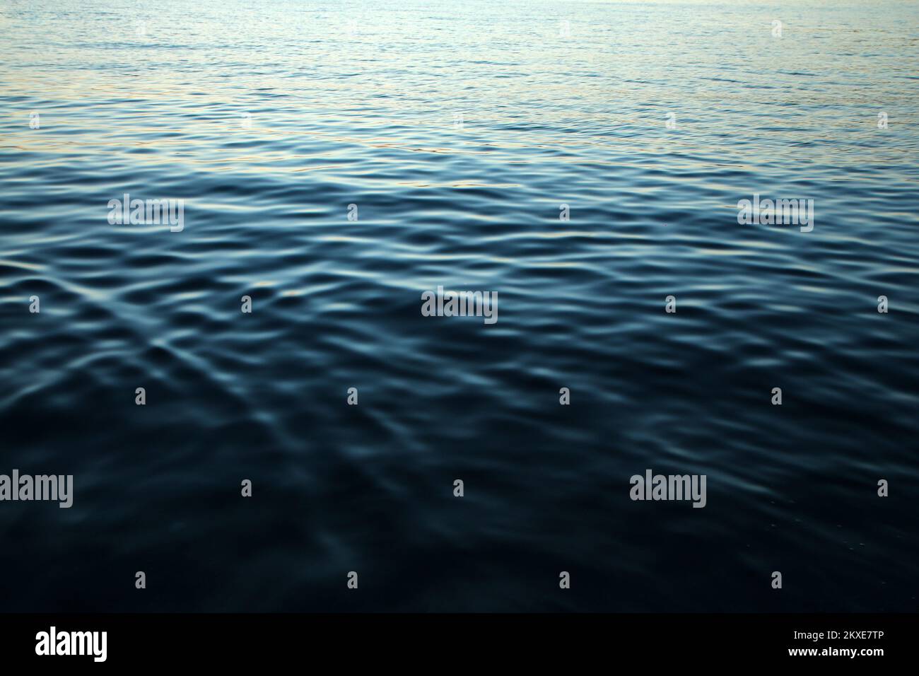 Il particolare della superficie calma del mare con le piccole onde durante la sera, mentre il sole è già sceso e le sfumature blu è venuto. Foto Stock