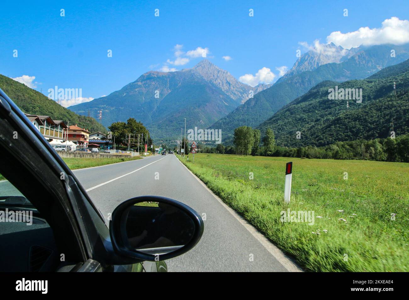 Guidare l'auto verso la valle alpina in Italia durante il viaggio estivo. Foto Stock