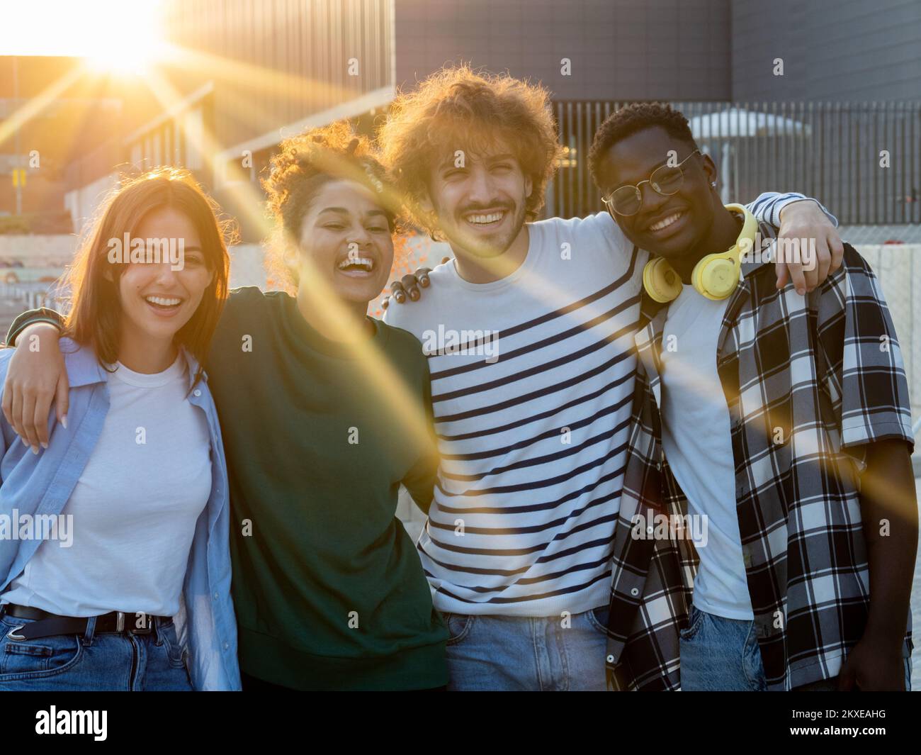Gruppo di giovani amici multietnici che si sono godenti un bel momento durante un tramonto in città. Migliori amici Foto Stock