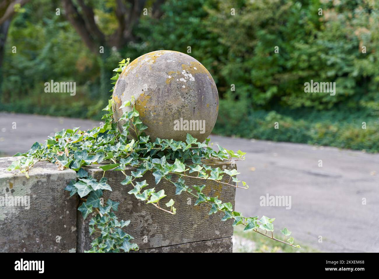 colonna con palla ricoperta di edera come decorazione su un sentiero in un parco pubblico Foto Stock