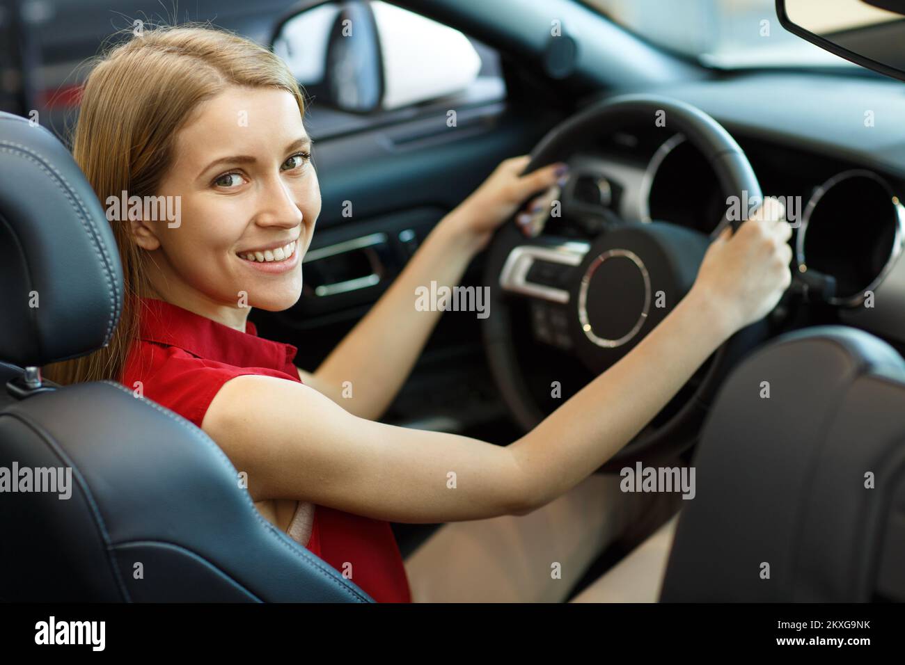 Vista dal retro della cliente femminile che prova l'automobile costosa in berlina auto Foto Stock