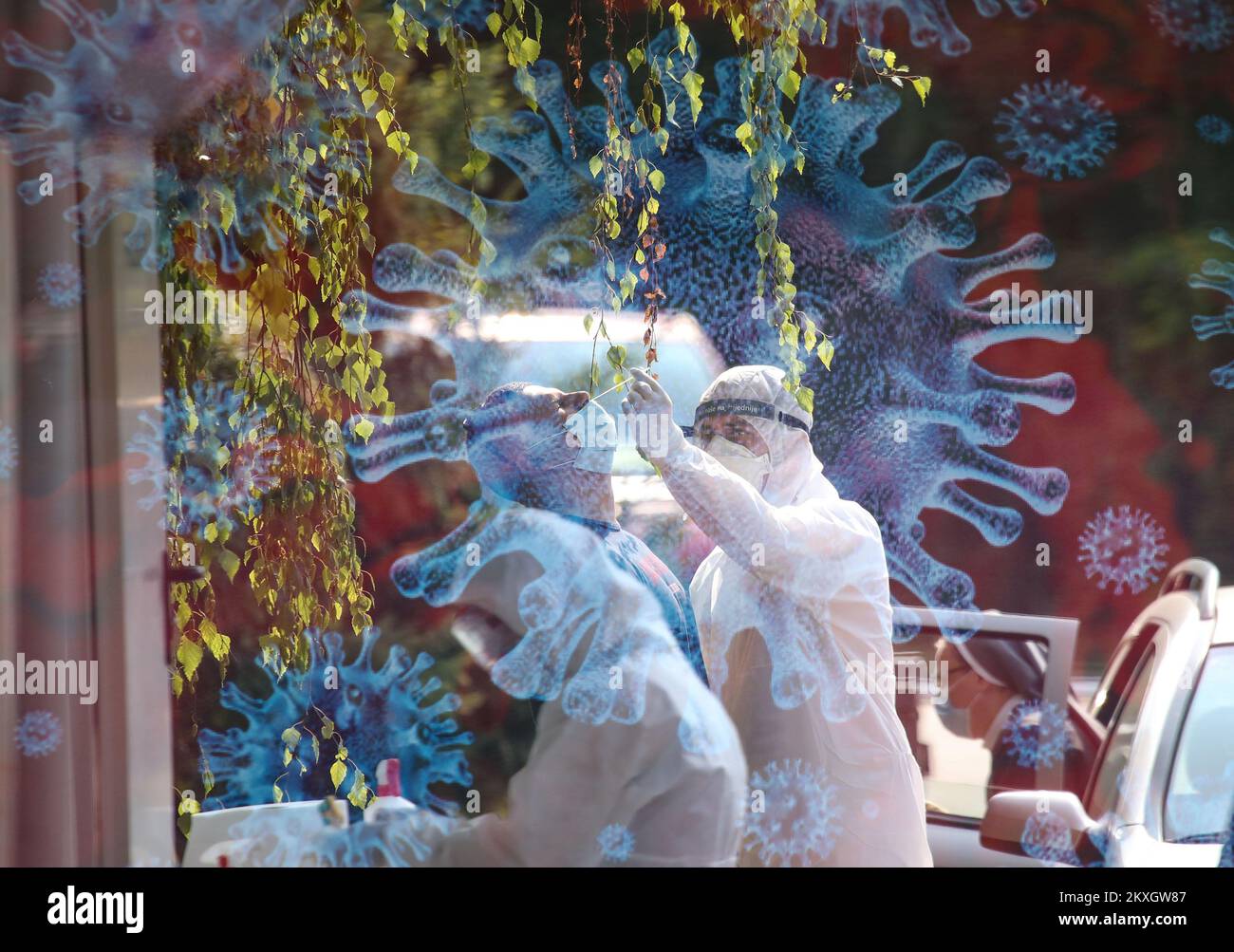 LLUSTRATION - PRESA CON DOPPIA ESPOSIZIONE. Nell'Istituto di insegnamento per la salute pubblica 'Dr. Andrija Stampar', i dipendenti stanno testando i cittadini. Diagnostica del coronavirus drive-in per velocizzare la diagnosi e aumentare il numero di persone testate. Le persone non escono dall'auto durante questo test, il che aumenta il livello di sicurezza della persona sottoposta a test e dell'operatore sanitario. Il virus che causa COVID-19 è nella maggior parte dei casi trasmesso attraverso goccioline che si formano quando una persona infetta tosse, starnuti o esalazioni. Queste goccioline sono troppo pesanti per volare attraverso l'aria e cadere rapidamente al Foto Stock