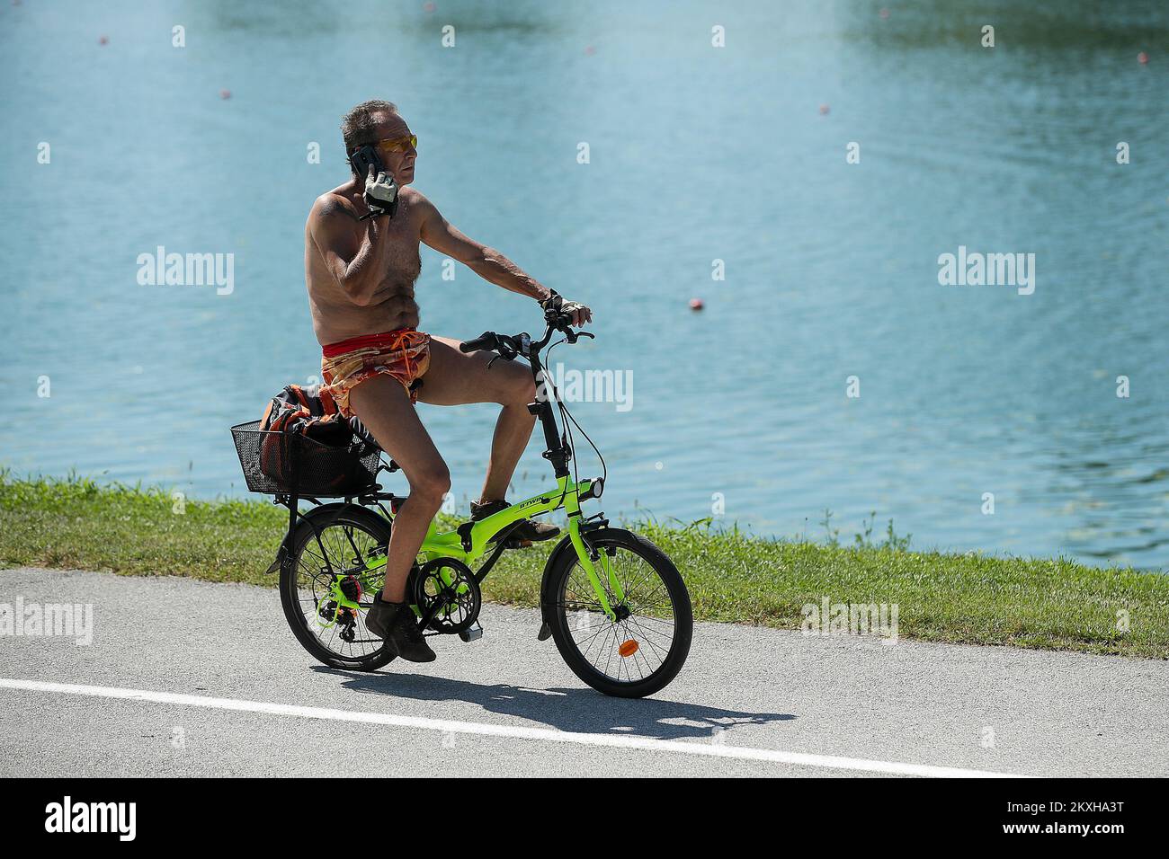 Un uomo senza camicia è stato visto in bicicletta parlando su un telefono cellulare intorno al lago Jarun a Zagabria, Croazia il 22 agosto 2020. Molti abitanti di Zagabria approfittarono di un'altra giornata calda e soleggiata per godersi il lago Jarun nonostante un numero crescente di infezioni da coronavirus. Foto: Goran Stanzl/PIXSELL Foto Stock