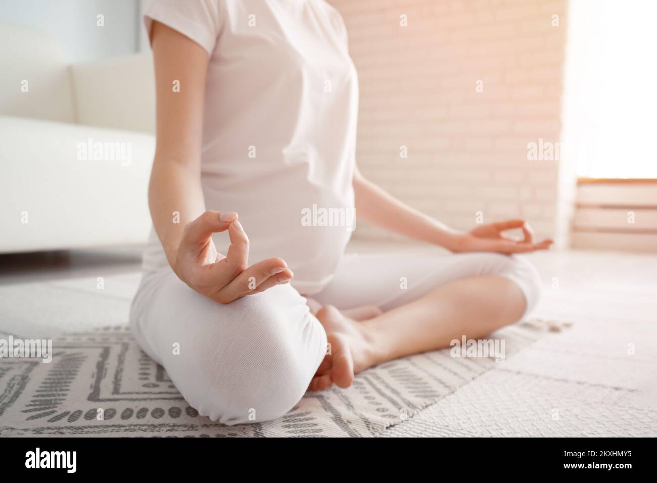 Calma donna incinta medita seduta in posizione lotus sul pavimento con tappeto a casa Foto Stock