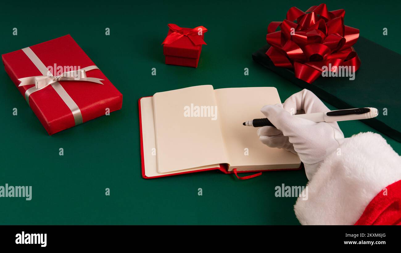 Le mani di Babbo Natale che scrivono la sua lista in vista orizzontale, copi lo spazio per mock in su nell'ordine del giorno aperto Foto Stock