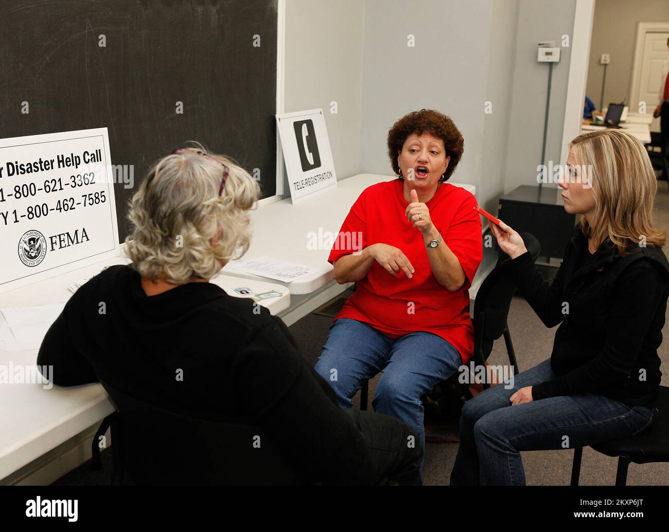 Allagamento grave tempesta Tornado - Center Point, Ala. , 3 febbraio 2012 all'interno del centro di recupero di disastro di FEMA, gli interpreti di linguaggio di segno con il reparto di Alabama dei servizi di Rehab, Wanda Cobb (c) e Alice Moss (r) assistono un superstite sordi usando il linguaggio di segno ed un telefono astuto per registrare per l'assistenza di FEMA. FEMA sta sostenendo il recupero dalle tempeste severe, dai tornado, dai venti in linea retta e dalle inondazioni che hanno danneggiato o distrutto parti dell'Alabama durante il periodo di 22-23 gennaio 2012. .. Fotografie relative a disastri e programmi, attività e funzionari di gestione delle emergenze Foto Stock