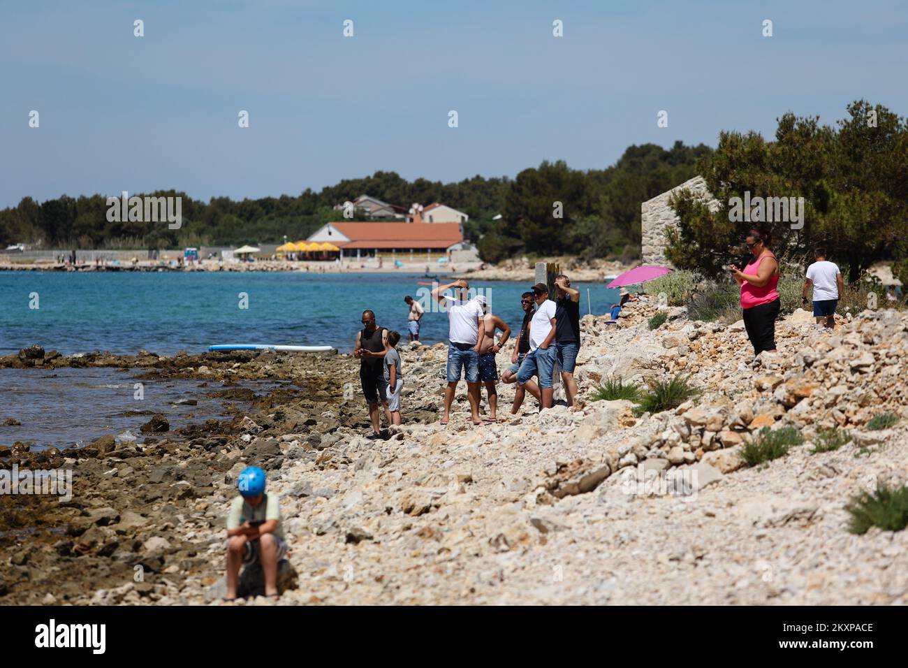 La gente è vista mentre guarda i vigili del fuoco della Brigata del fuoco pubblico Biograd na Moru mentre estingueva il fuoco che scoppiò sullo yacht nelle immediate vicinanze di Crvena Luka, vicino Biograd na Moru, Croazia il 27 giugno 2021. Al momento dello scoppio dell'incendio, vi erano otto cittadini austriaci sullo yacht noleggiato. Scapparono saltando in mare e nuotarono inscesi a riva. Foto: Marko Dimic/PIXSELL Foto Stock