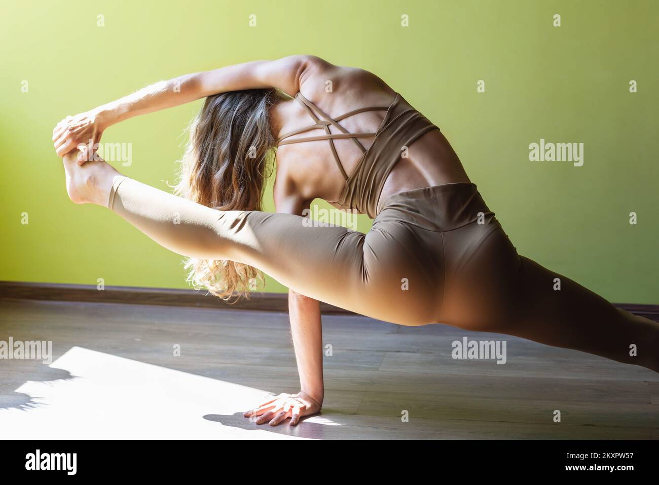 Una giovane donna che conduce uno stile di vita sano e pratica yoga, esegue l'esercizio Vishwamitrasana, equilibrio di forza e flessibilità, si allena su t Foto Stock