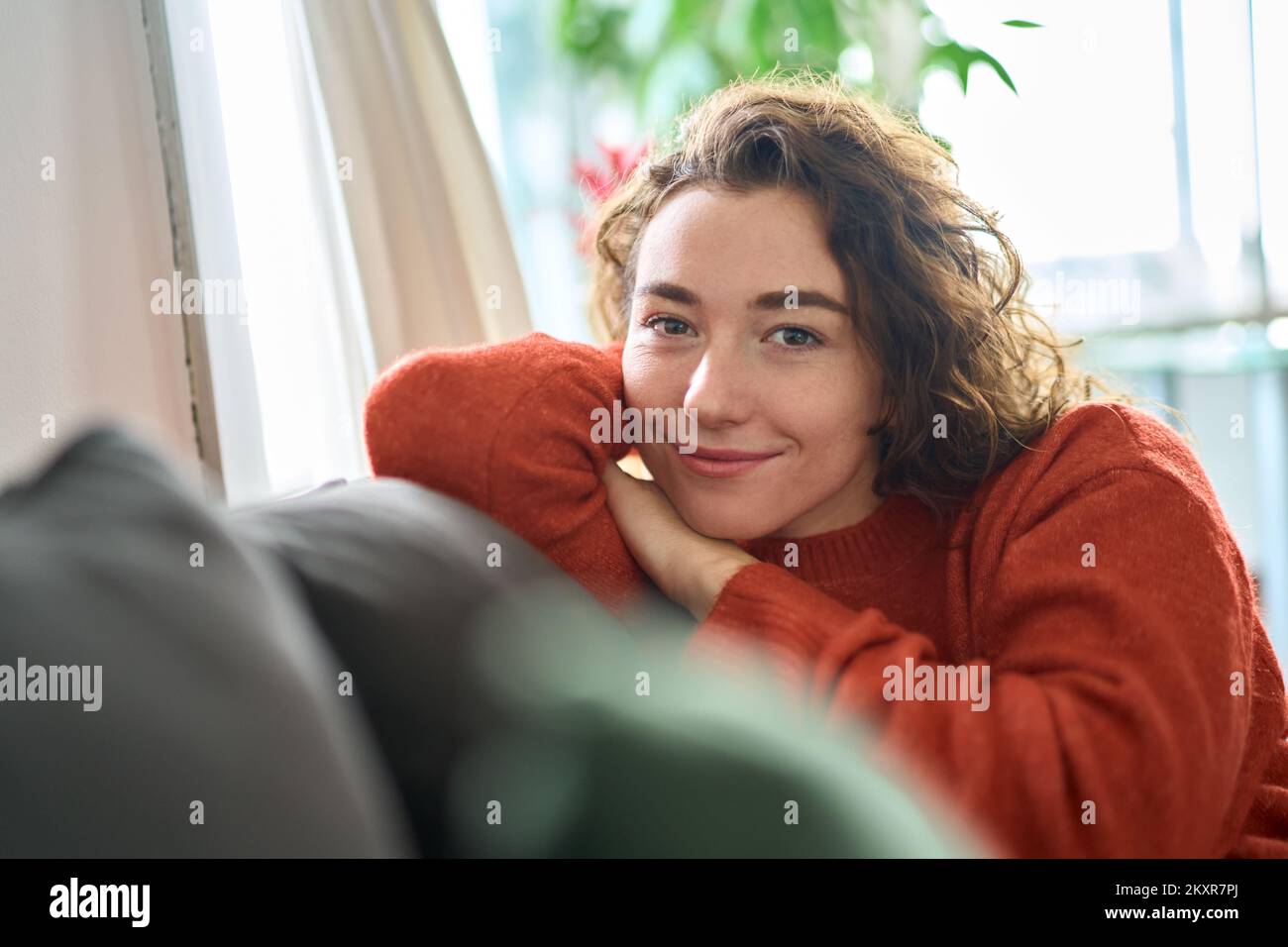Giovane felice bella donna che si rilassa seduto sul divano a casa. Verticale Foto Stock