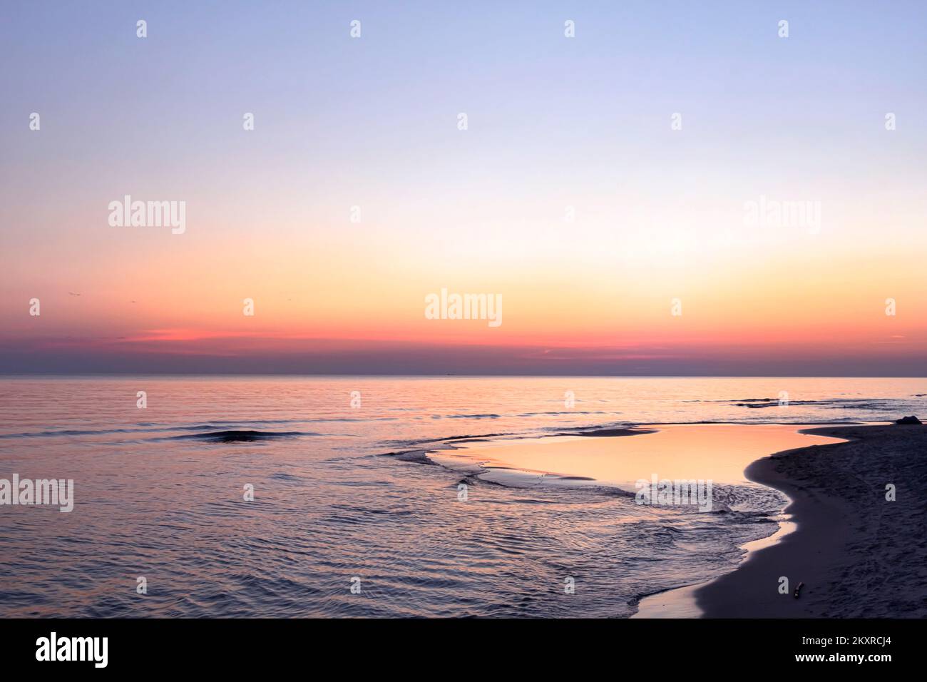 Mare Baltico vuoto spiaggia paesaggio orizzonte arancione sopra l'acqua. Panorama marino con cielo all'alba. Bella alba sul mare, riflessi nella calma Foto Stock