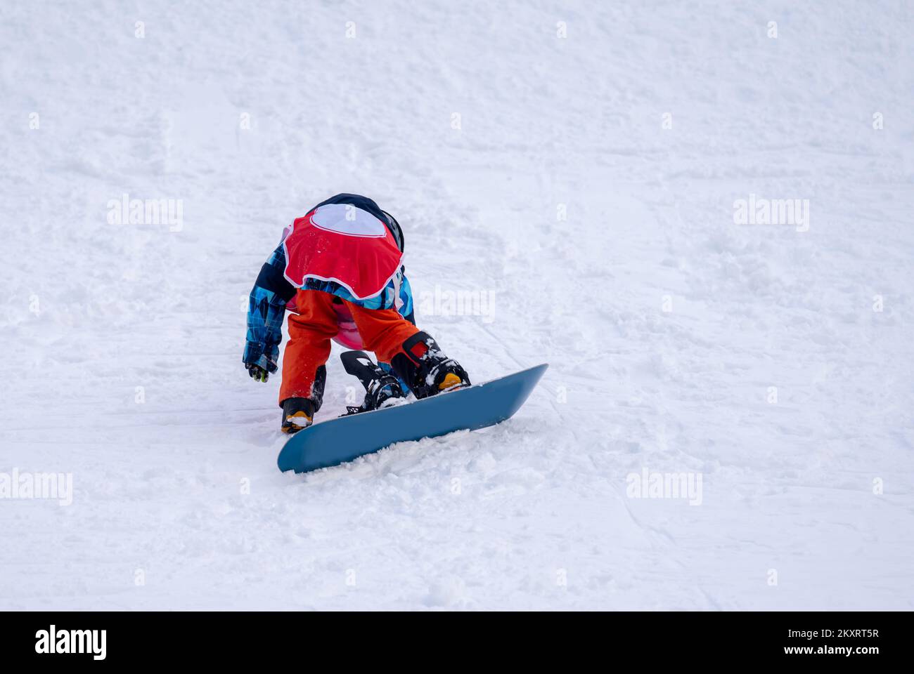 Persona con snowboard sulla neve. Un bambino asiatico sta cadendo sul terreno. Sport invernali con spazio copia. Foto Stock