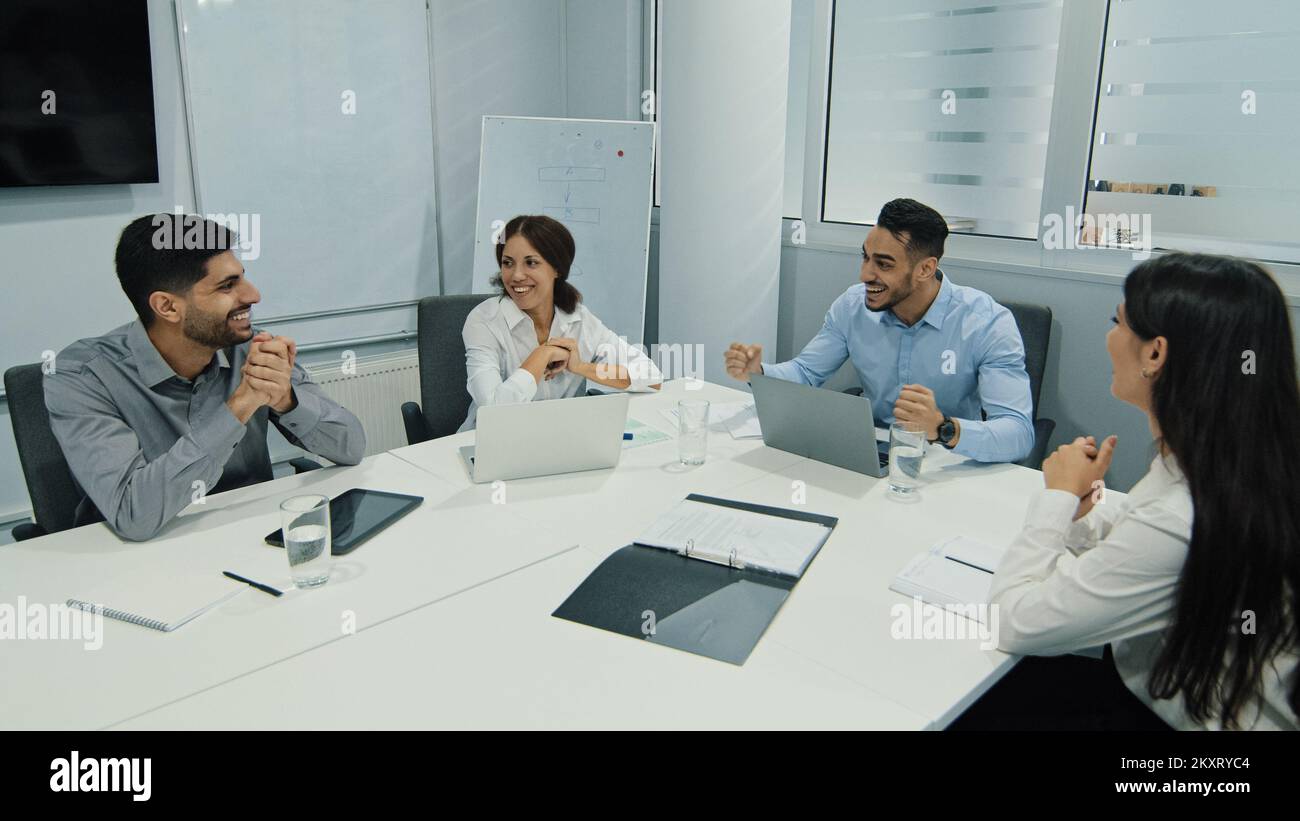 Un uomo d'affari motivato e arabo, leader del team, che spiega la strategia di sviluppo aziendale a giovani colleghi diversi. Gente multirazziale riuscita di affari Foto Stock