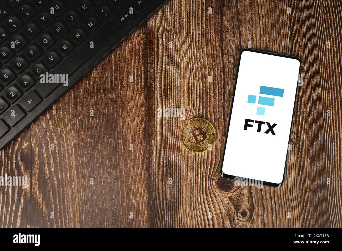 Logo dell'app di scambio criptovaluta FTX sullo schermo dello smartphone con Bitcoin oro e tastiera su retro in legno. VARSAVIA, POLONIA - 17 FEBBRAIO 2021 Foto Stock
