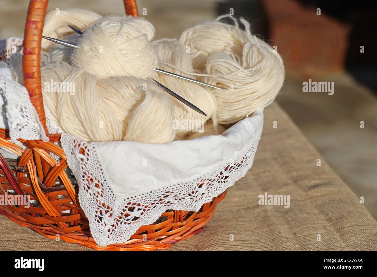 Il cestello contiene fili per maglieria, aghi per maglieria e una sfera di filo. Foto Stock