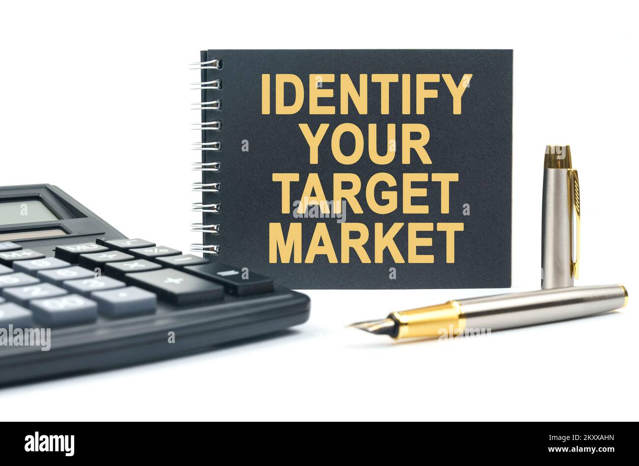 Affari e finanza. Su uno sfondo bianco, c'è una calcolatrice, una penna e un notebook nero con l'iscrizione - IDENTIFICARE IL VOSTRO MERCATO DI DESTINAZIONE Foto Stock