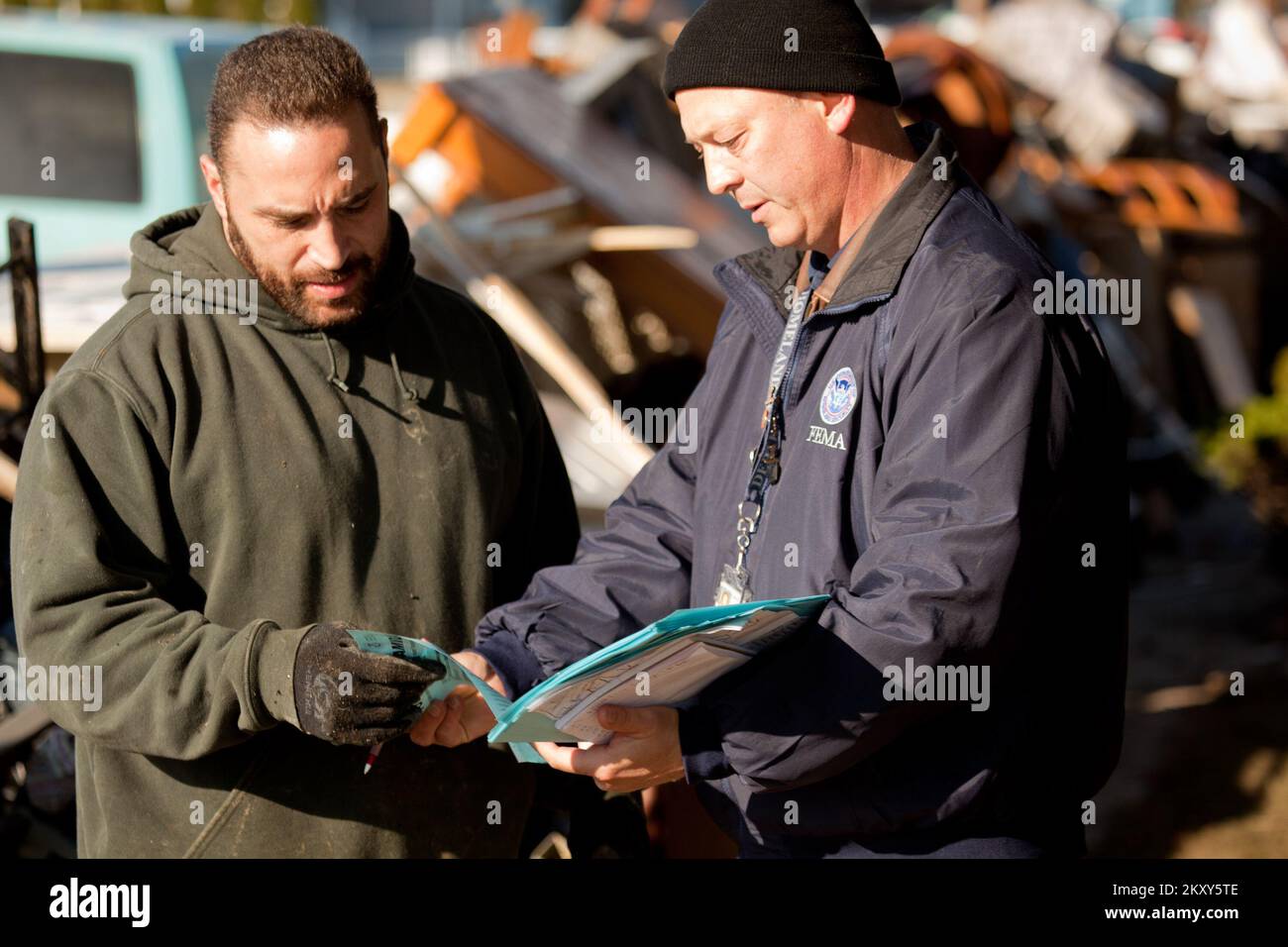 Atlantic Beach, N.Y., 9 novembre 2012 FEMA Community Relations Worker, Shannon Arledge condivide le informazioni di registrazione per l'assistenza in caso di disastri con il sopravvissuto all'uragano, GJ McGreevy ad Atlantic Beach, New York. L'uragano Sandy ha creato alluvioni diffuse, interruzioni di corrente e devastazioni a Long Island, New York. Andrea Booher/FEMA. L'uragano Sandy di New York. Fotografie relative a disastri e programmi, attività e funzionari di gestione delle emergenze Foto Stock
