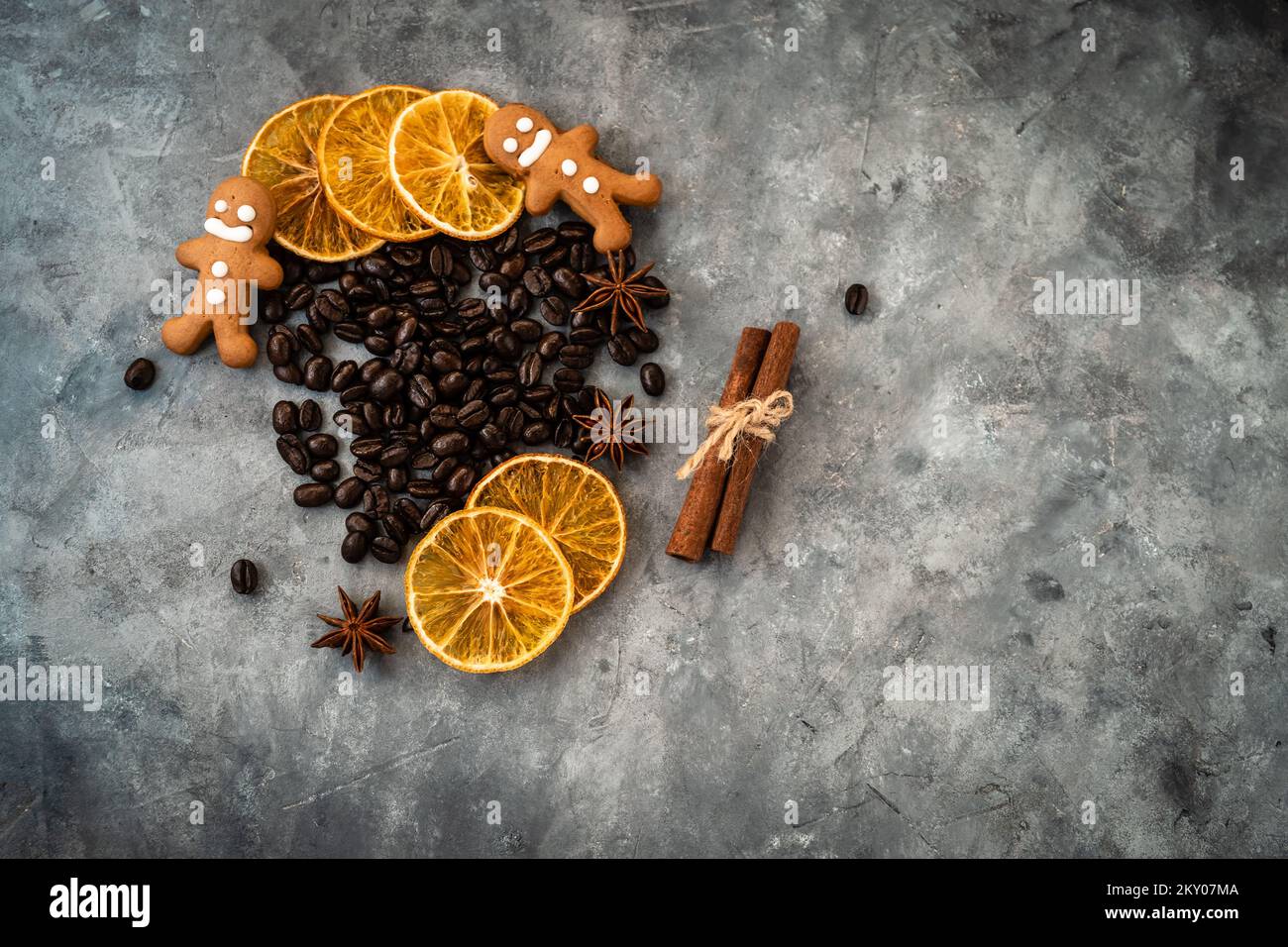 Composizione natalizia con chicchi di caffè, affettati di arance essiccate, biscotti e cannella stick su sfondo grigio. Tiro piatto da sopra wit Foto Stock