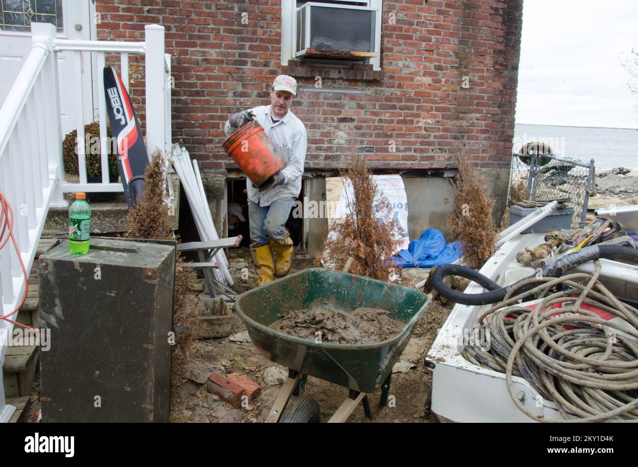 Atlantic Highlands, N.J., 24 novembre 2012 Joe Barry, un volontario del Comitato Metodista Unito su Soccorso, aiuta un proprietario di abitazione a pulire dopo che l'uragano Sandy ha lavato via le pareti esterne e completamente ha riempito il seminterrato. New Jersey Hurricane Sandy. Fotografie relative a disastri e programmi, attività e funzionari di gestione delle emergenze Foto Stock
