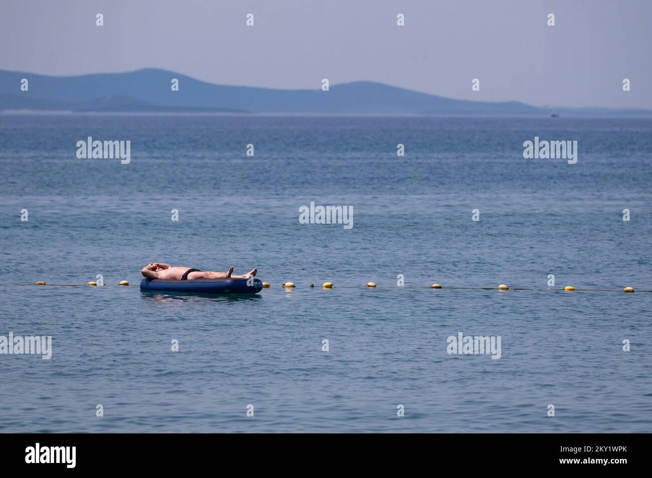 Un uomo galleggia in mare mentre un'onda di calore raggiunge il paese di Zara, Croazia, il 21 giugno 2022. Foto: Dino Stanin/PIXSELL Foto Stock