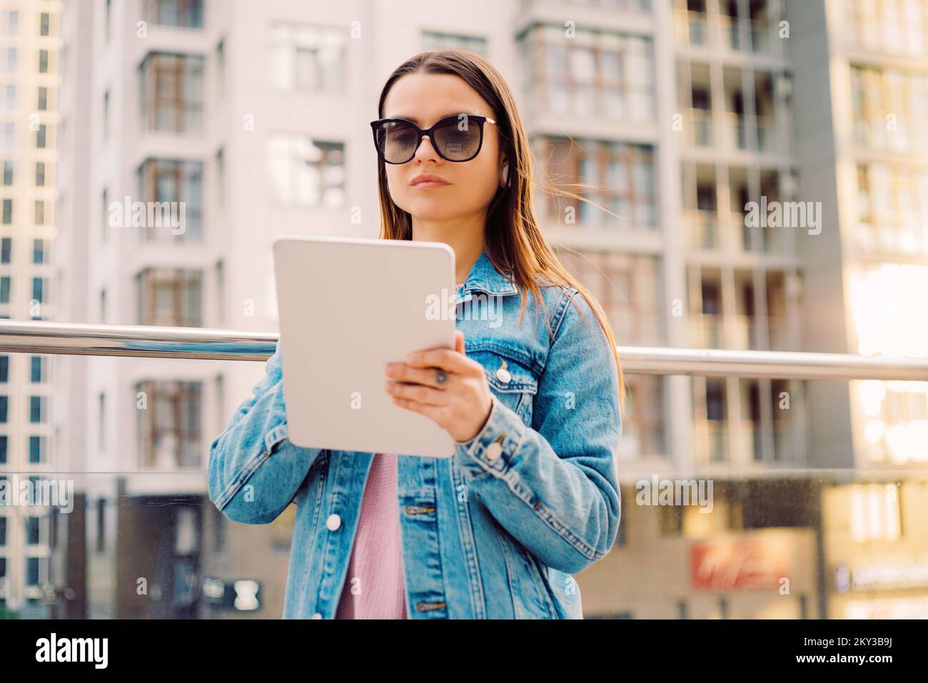 Giovani donne d'affari millennial in occhiali che camminano nel quartiere finanziario della città utilizza tablet digitali nei social network, connessione, dati, display digitale Foto Stock