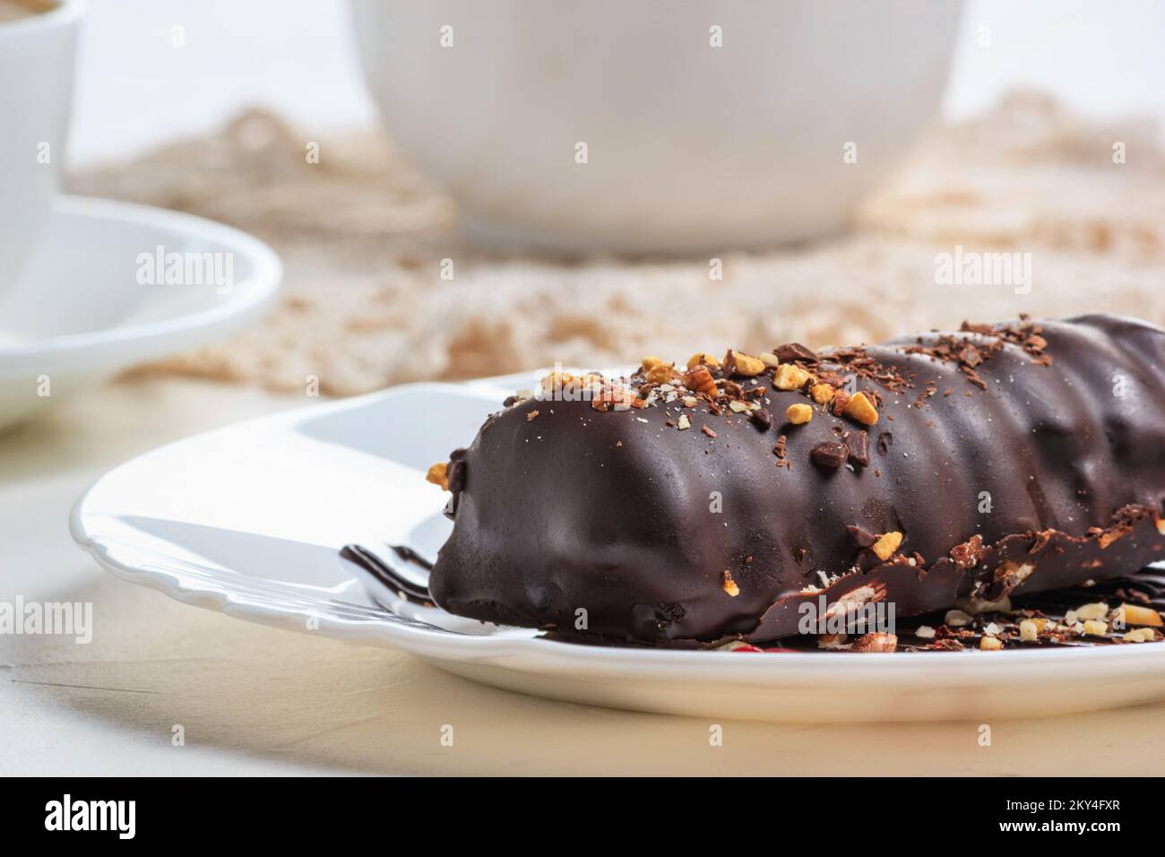 Torta da dessert su piatto bianco, primo piano, messa a fuoco selettiva. Torta ricoperta di cioccolato e noci. Ancora la vita nello stile di una chiave alta Foto Stock