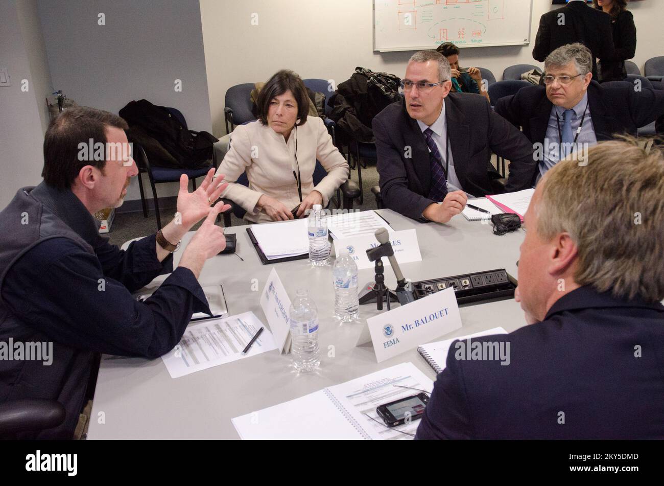 Queens, N.Y., 5 marzo 2013 la FEMA ha ospitato un team di gestione delle emergenze francese presso il JFO (Joint Field Office) di NY per informarli sulle operazioni di ripristino di emergenza per l'uragano Sandy. Tom Fargione (a sinistra), responsabile della sezione operazioni, discute la logistica della risposta ai disastri. K.C.WILSEY/FEMA. L'uragano Sandy di New York. Fotografie relative a disastri e programmi, attività e funzionari di gestione delle emergenze Foto Stock