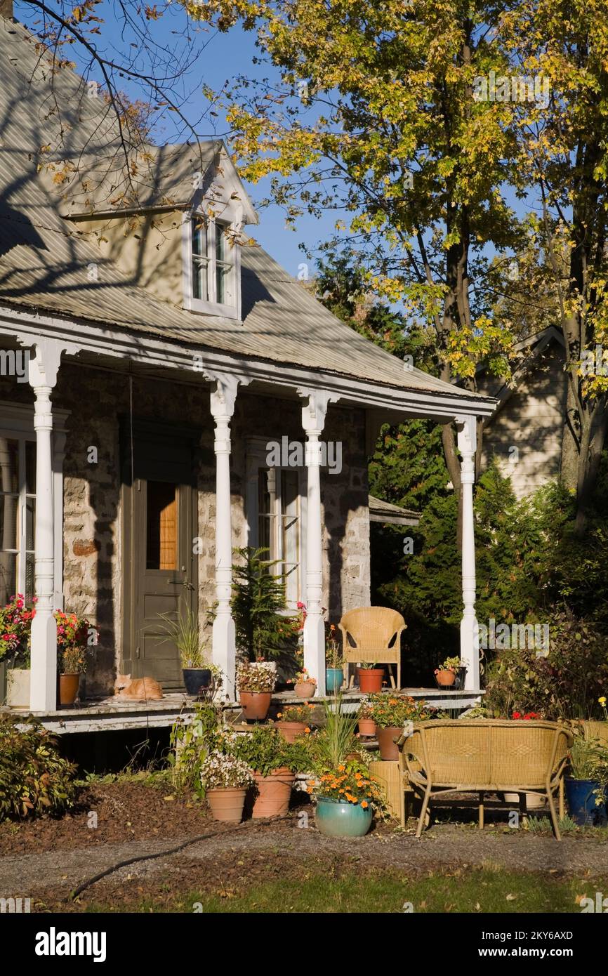 Vecchia casa a due piani 1700s con giardino paesaggistico e mobili da giardino in vimini in autunno. Foto Stock