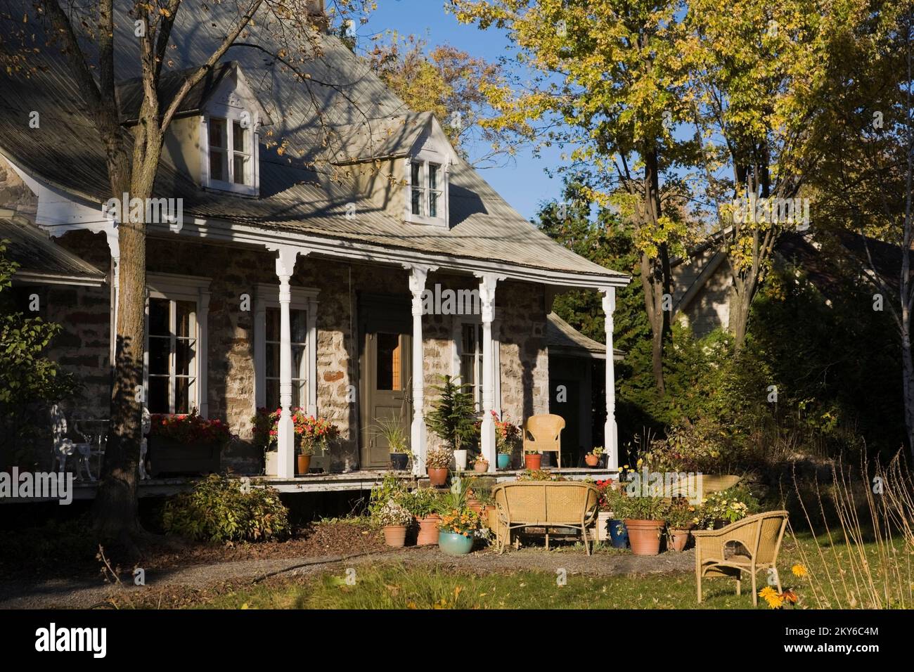 Vecchia casa a due piani 1700s con giardino paesaggistico e mobili da giardino in vimini in autunno. Foto Stock