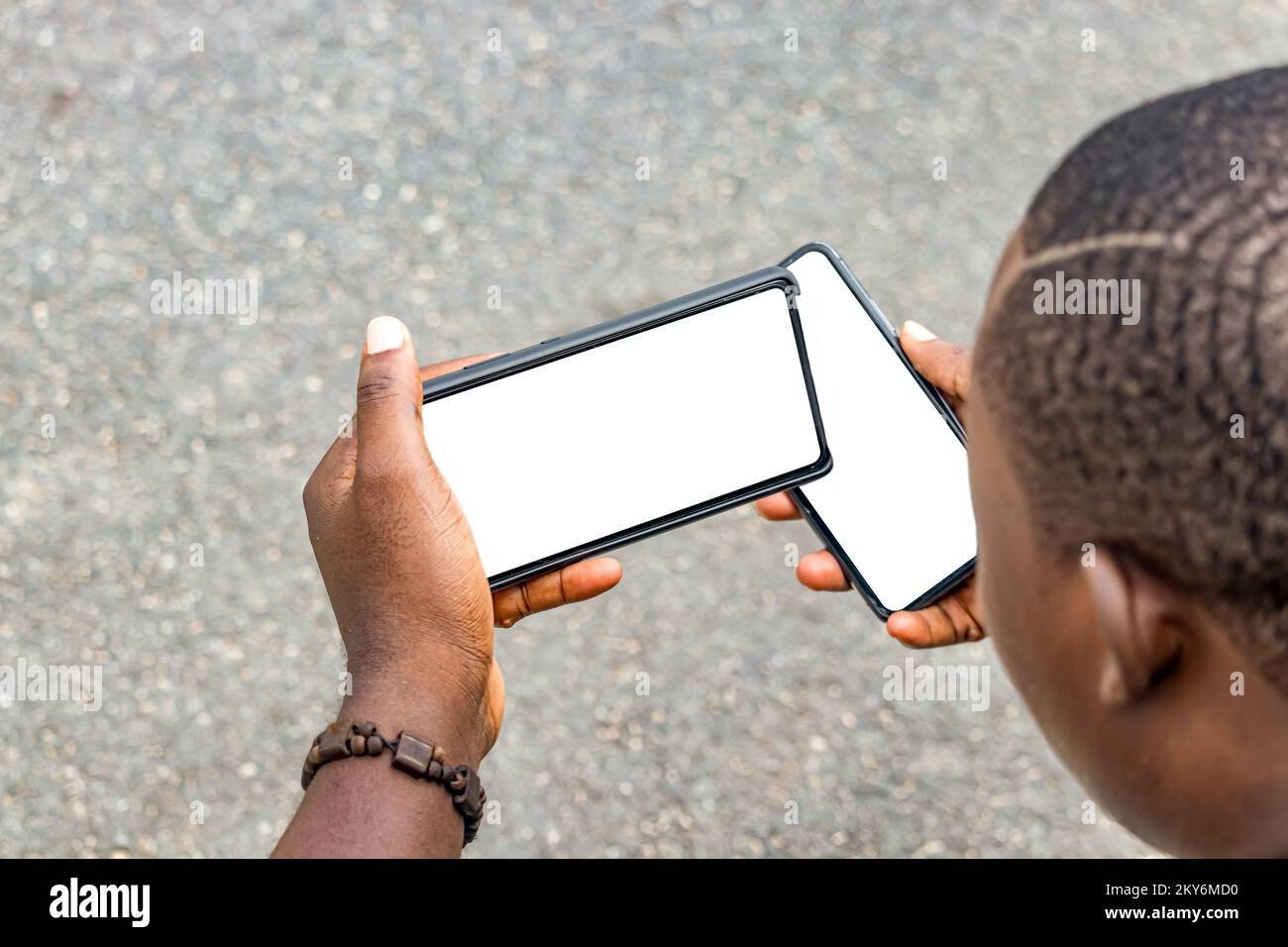 Jeune homme africain assis au parc et utilizant un téléphone intelligente. Foto Stock