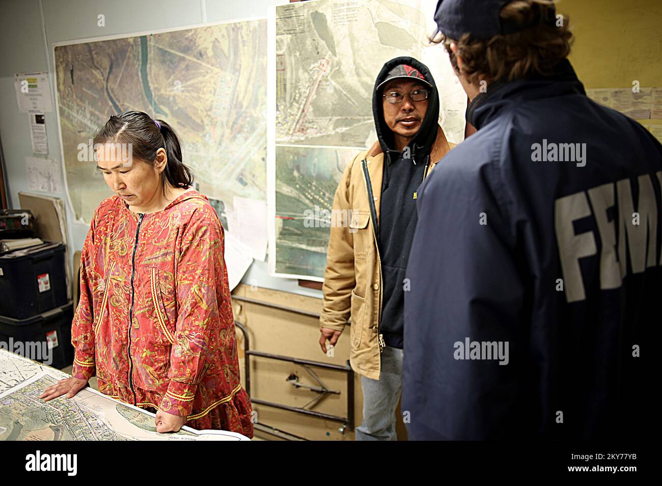Emmonak, Alaska, 15 luglio 2013 presso l'edificio comunale locale, il leader tribale Emmonak Olivia Moses (L) e il sopravvissuto al disastro Michael Andres (R) guarda la mappa delle pianure alluvionali dopo che gravi inondazioni hanno devastato la loro comunità. Gli individui e i proprietari di affari che hanno sostenuto le perdite nelle zone designate possono cominciare fare domanda per l'assistenza registrandosi in linea a www.disasterassistance.gov o denominando 1-800-621-FEMA. Adam DuBrowa/ FEMA.. Fotografie relative a disastri e programmi, attività e funzionari di gestione delle emergenze Foto Stock